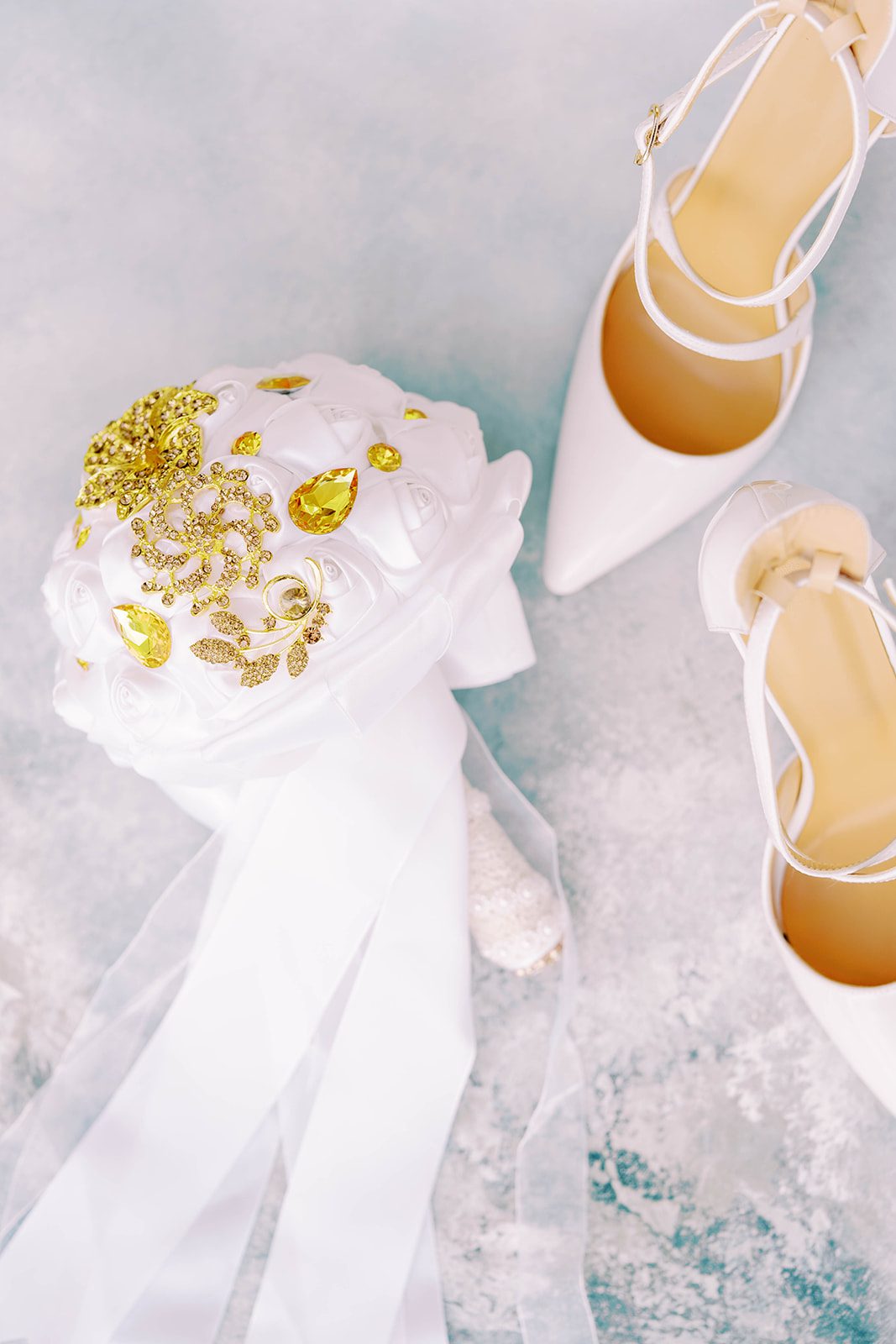 detail shot of bridals shoes and bouquet on a light blue background