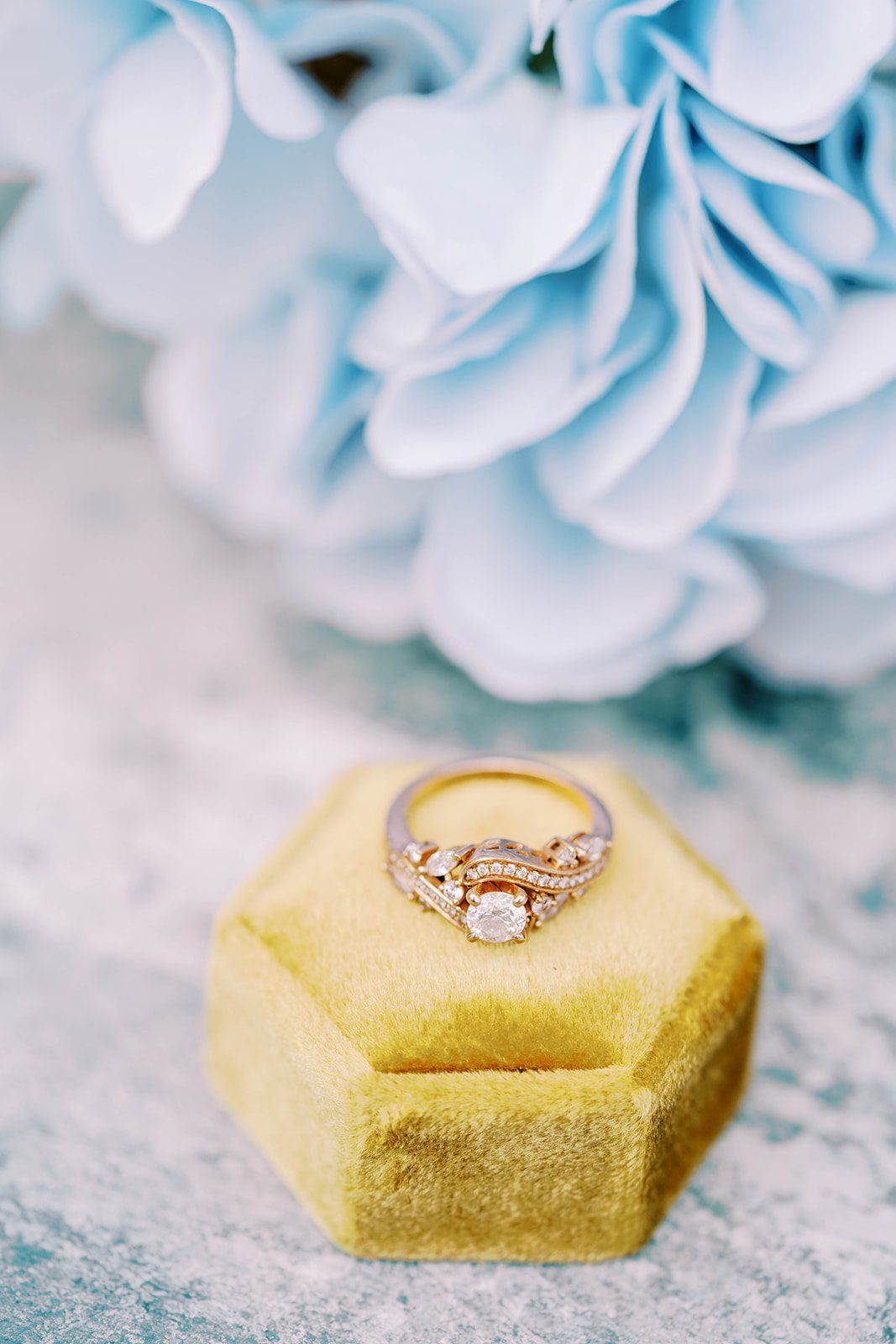 wedding ring sitting on a gold ring box with light blue florals in the background for a Tampa Florida wedding venue