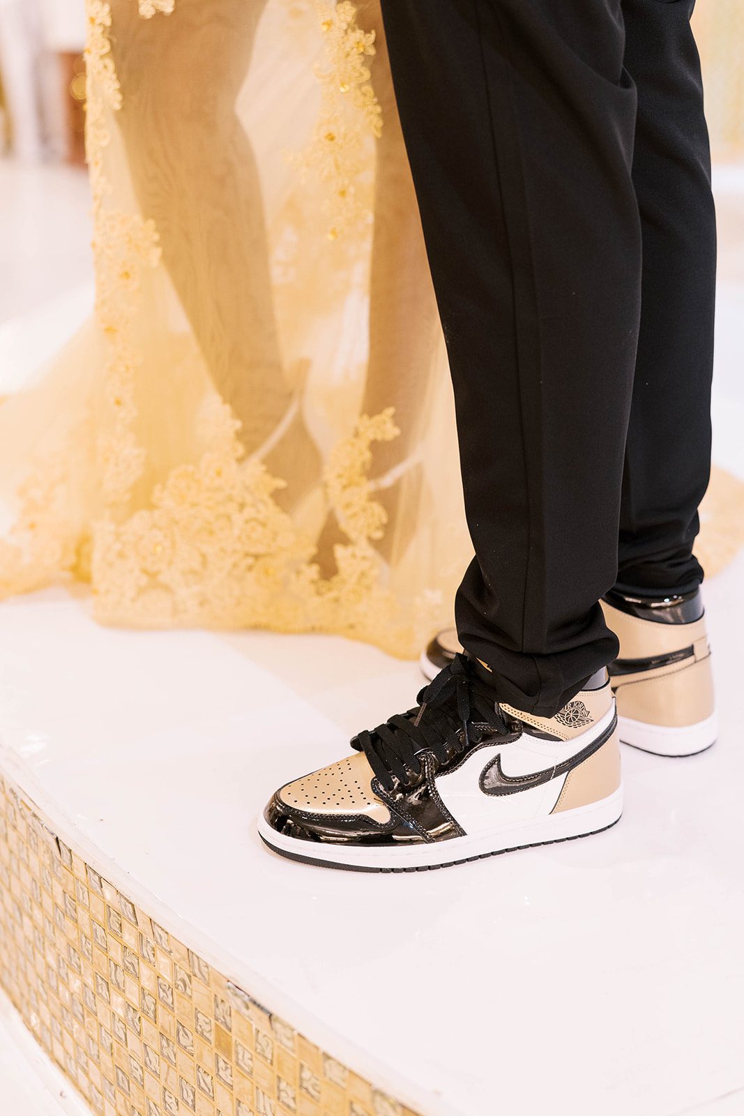 detail shot of grooms nike shoes that are gold and black to match his wedding suit