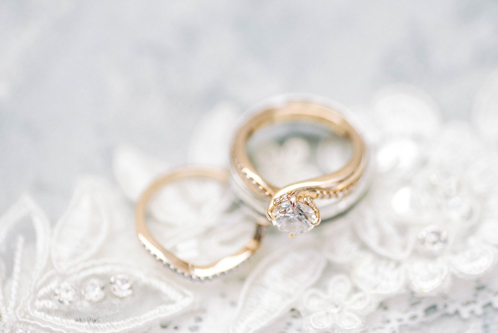 wedding ring detail shot with gold brides rings on top of lace veil 