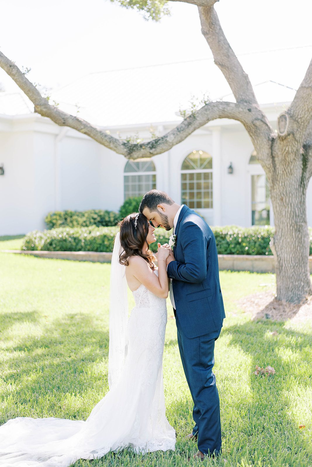 bride and groom outside of Harborside Chapel holding hands and brining their foreheads together on their Tampa wedding day captured by best Tampa wedding photographer