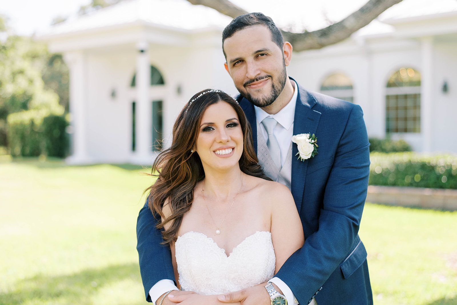 bride and groom standing on the grounds of Haborside chapel a Tampa wedding venue in Florida with the groom holding the bride as they both smile at the camera