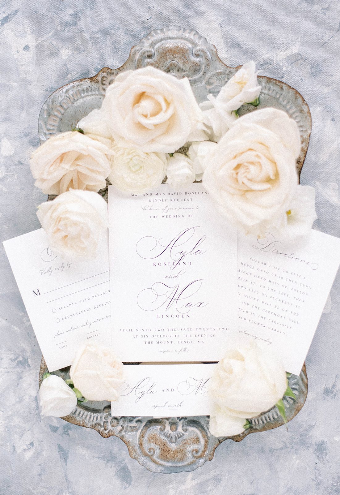 picture perfect wedding invitation on a silver platter with white roses detailing the wedding theme in the flatlay shot