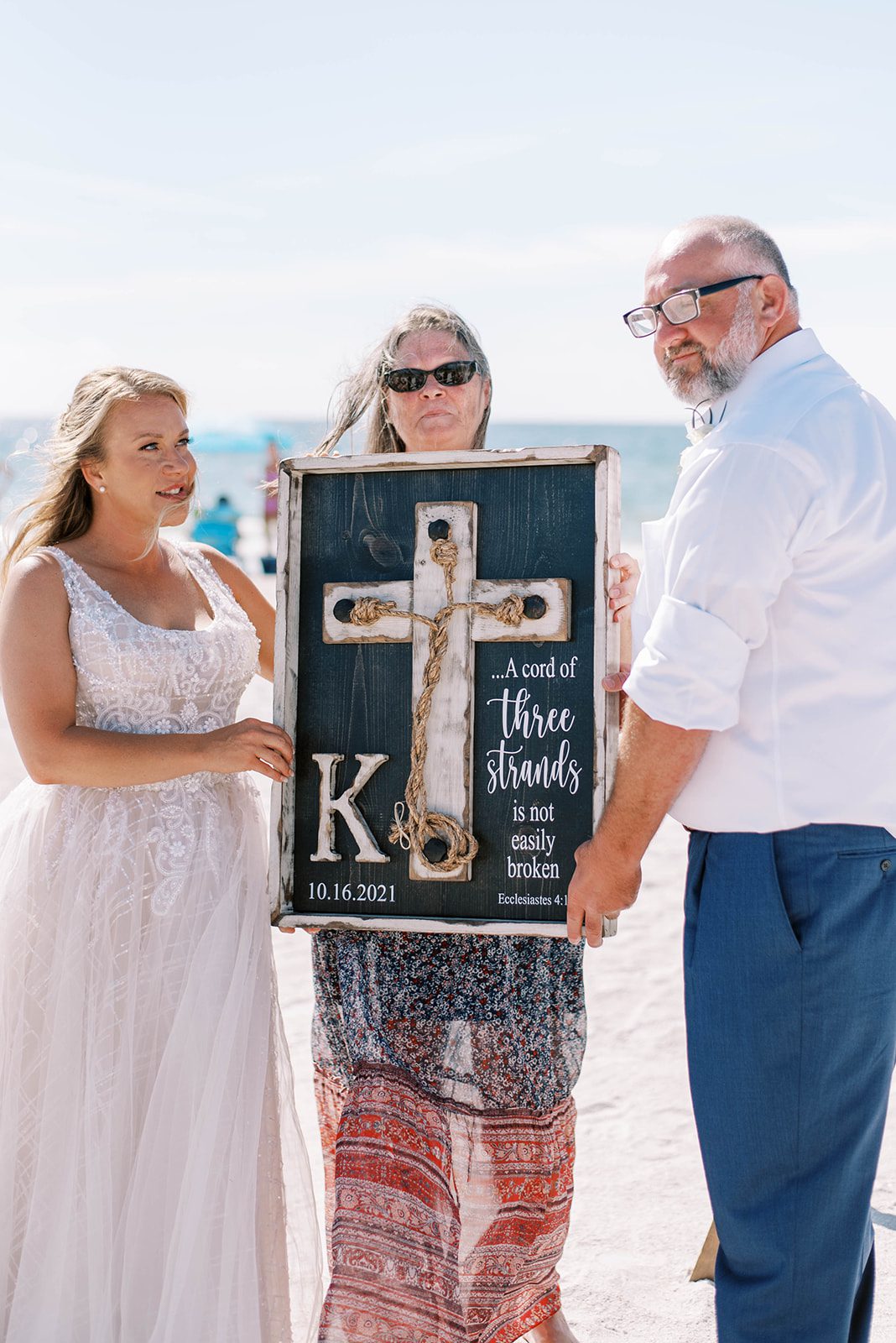 bride and groom holding a board representing the cord of three Christian wedding tradition