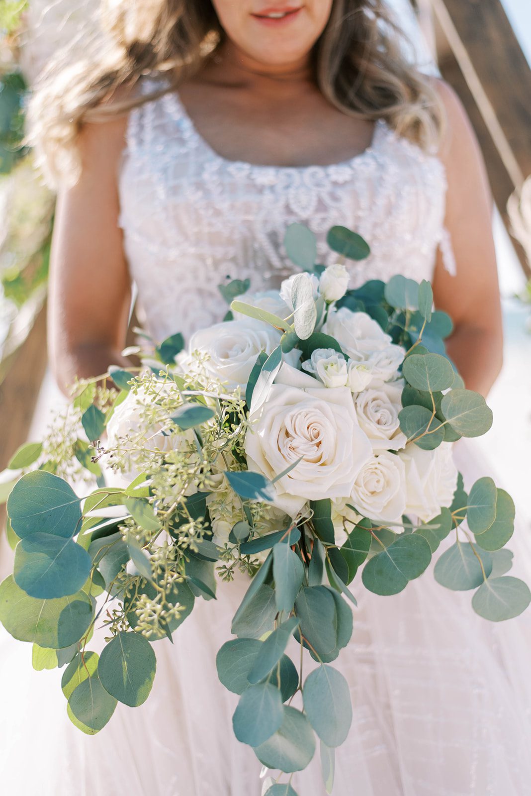 bride holding her wedding bouquet for her Florida beach wedding with the bouquet having white roses and eucalyptus