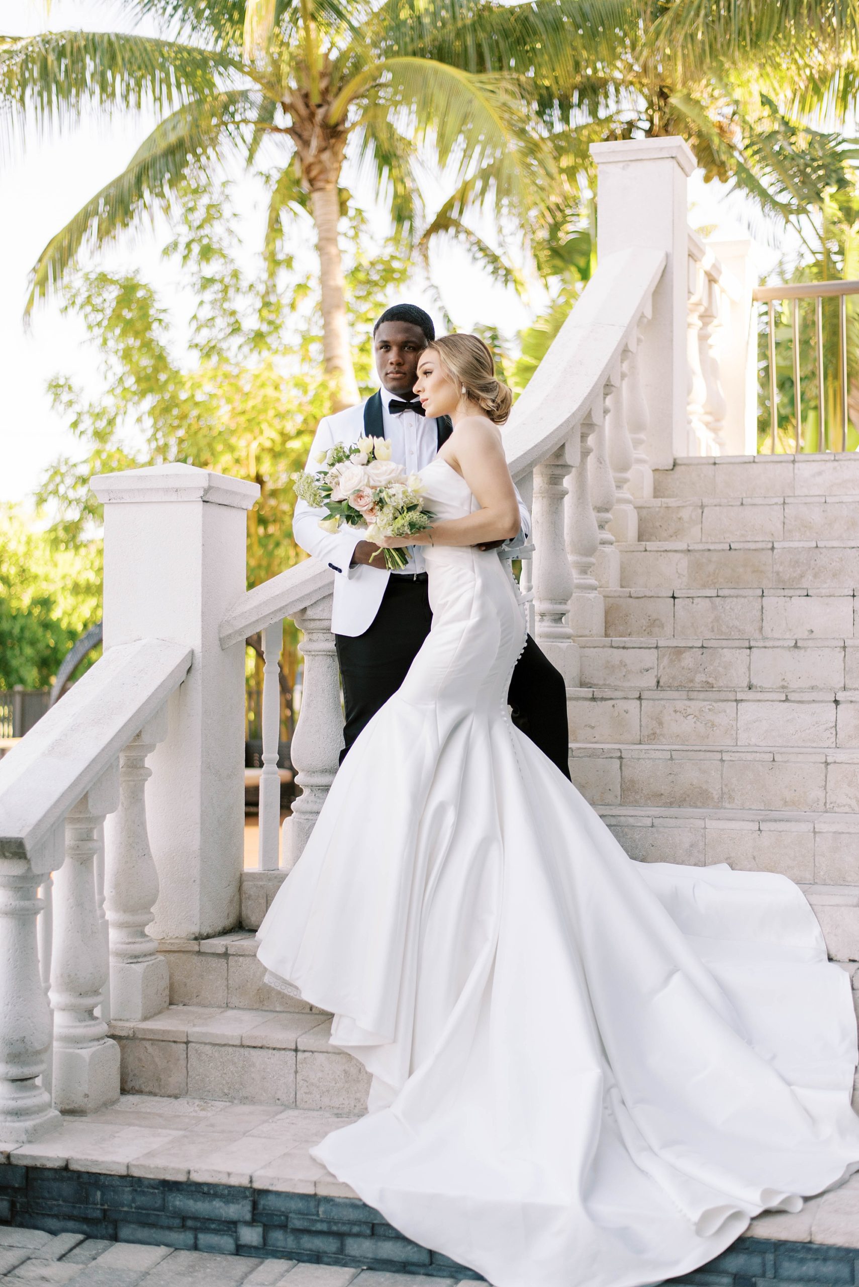 bride and groom stand on steps at Hotel Zamora for portrait with bride's dress draped down steps