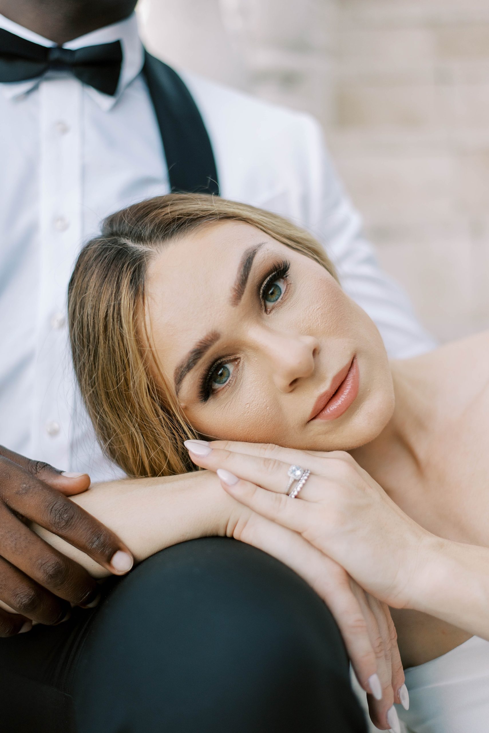 bride leans on groom's knee during wedding portraits