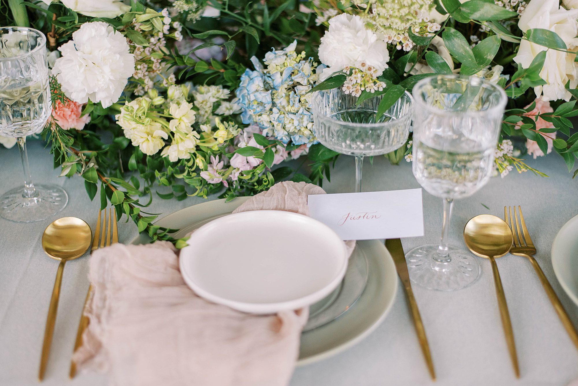 place setting with white plate, blush napkin, and floral centerpieces