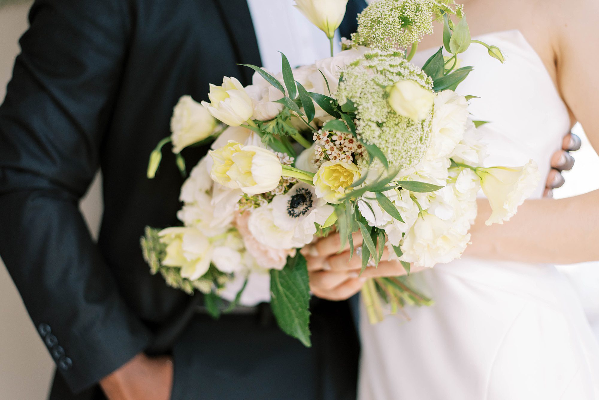 bride holds bouquet of ivory flowers and greenery
