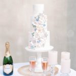 tiered wedding cake with pastel flowers and champagne