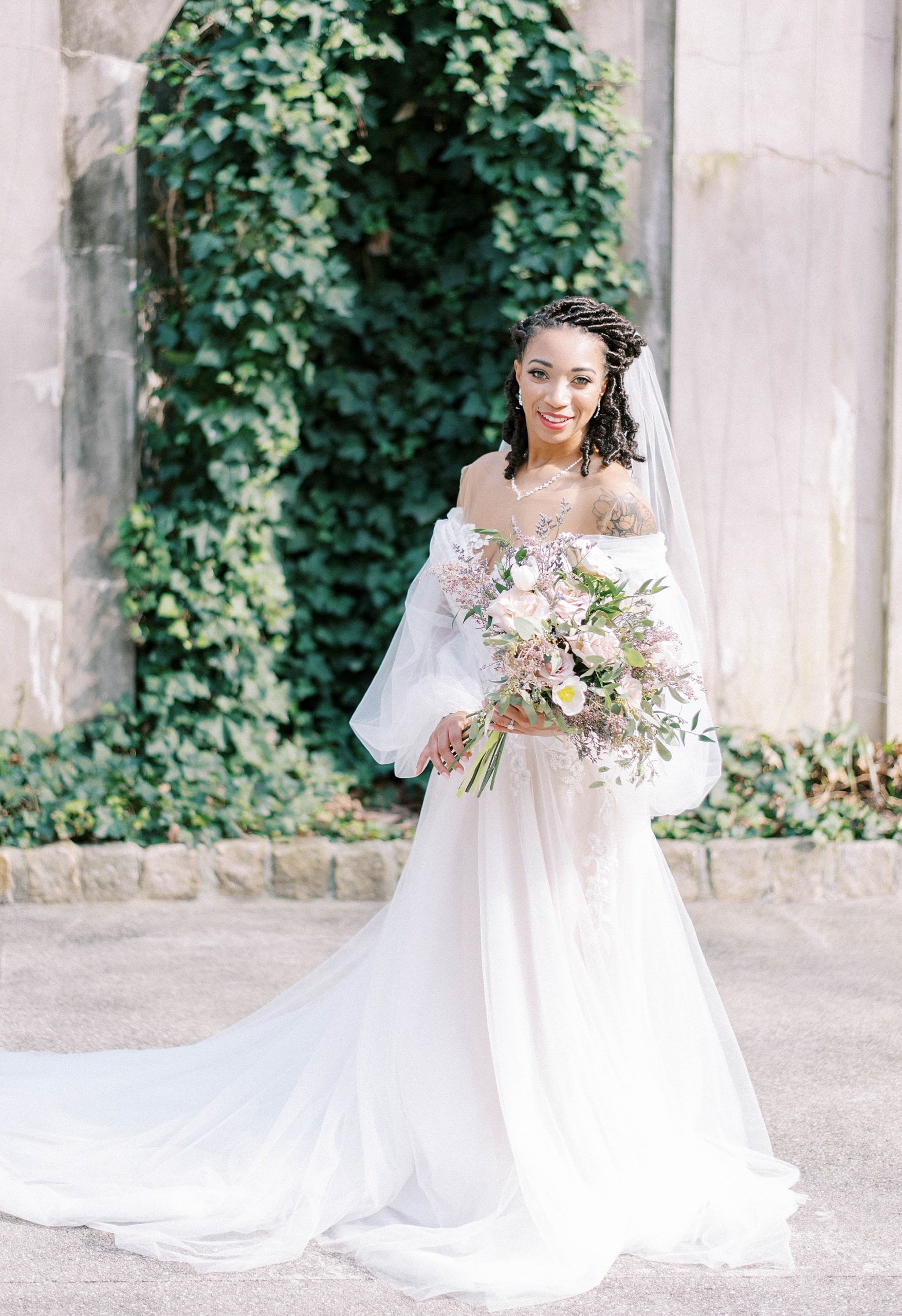 bride holds bouquet of pastel flowers in gardens at Swan House Atlanta