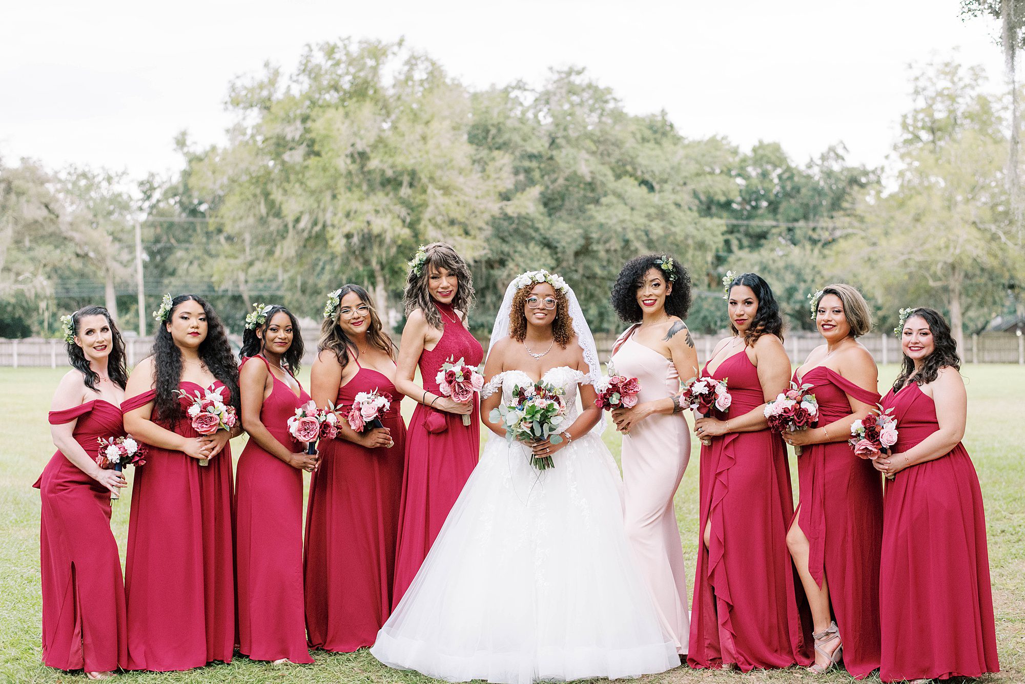 bride poses with bridesmaids in red gowns at Casa Lantana