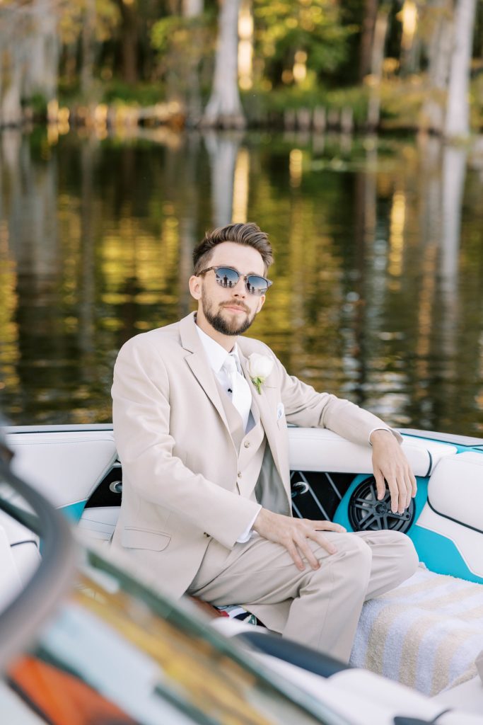 groom in tan suit arrives to wedding ceremony on boat in Florida