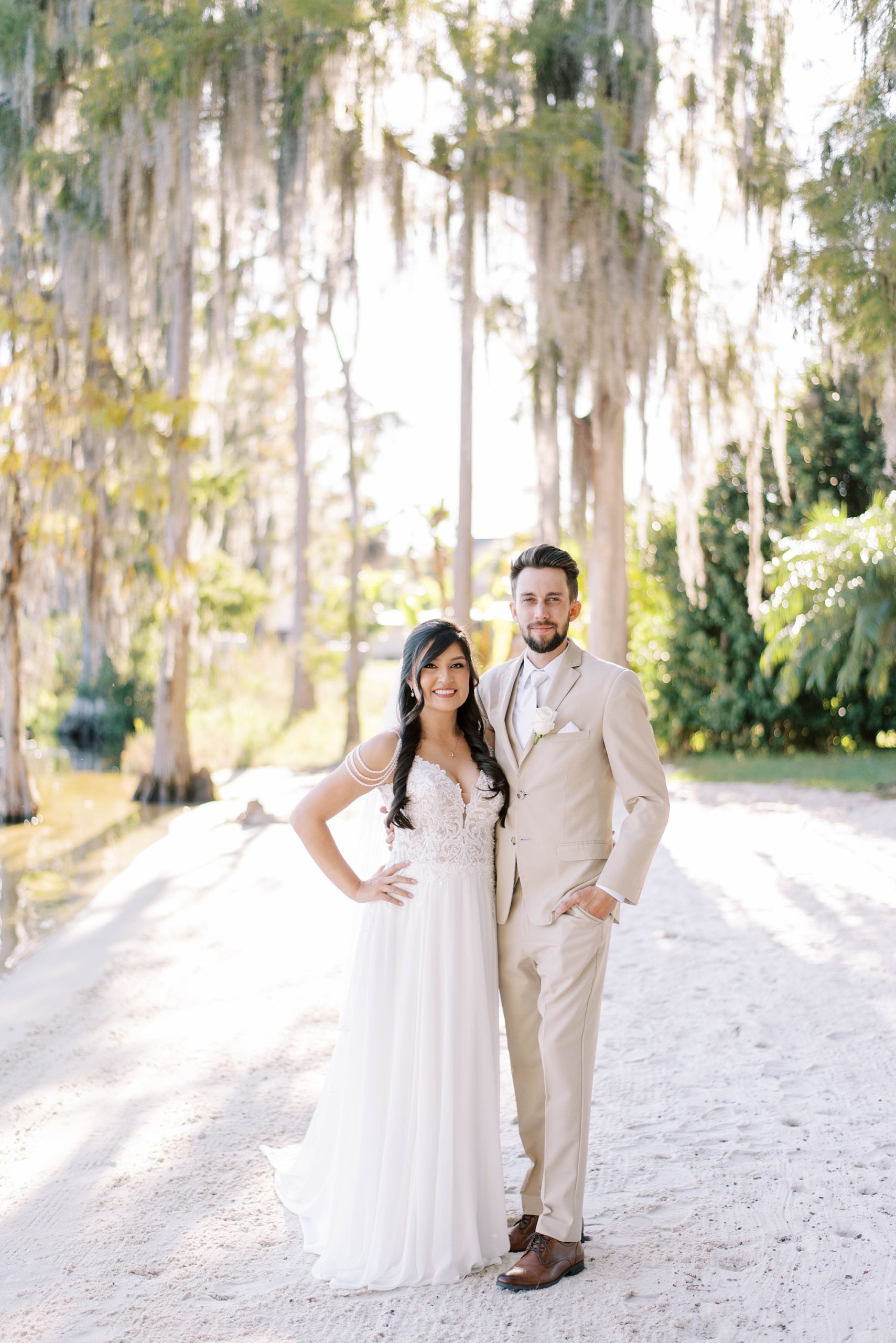 newlyweds pose on pathway under Spanish moss in Florida