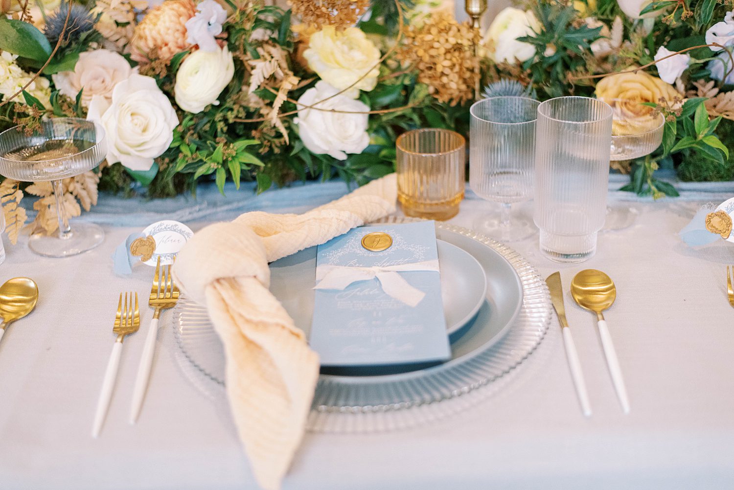 place settings with pastel blue wedding invitations and yellow flowers