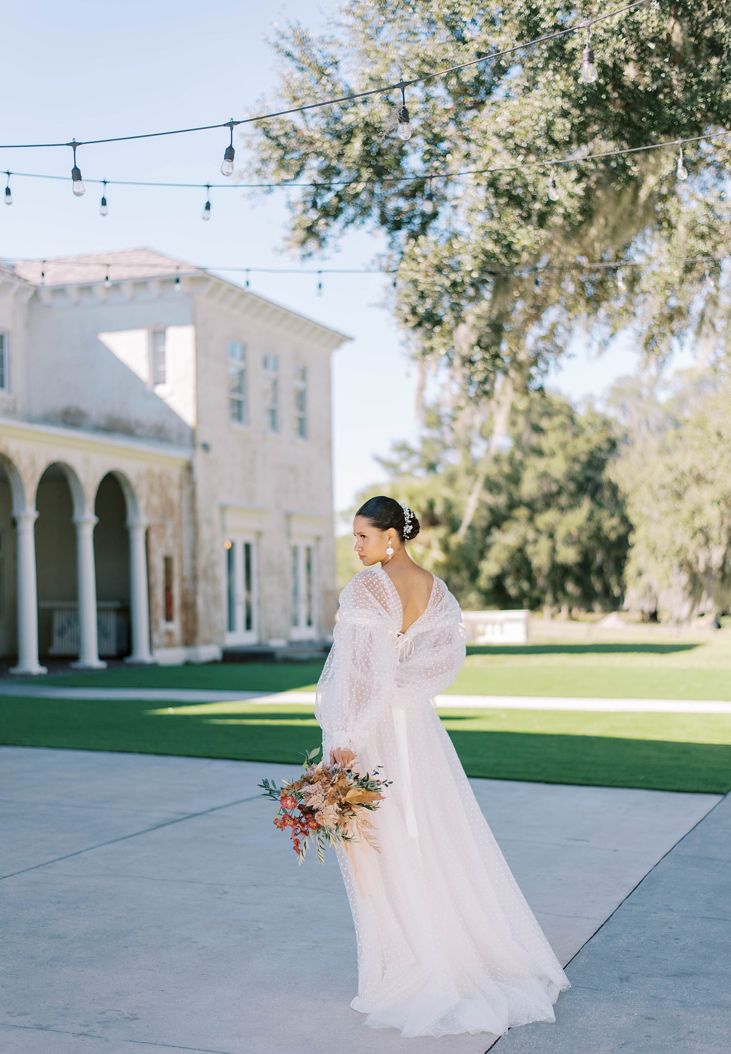 bride walks holding bouquet by side in courtyard during BellaCosa Lakeside wedding