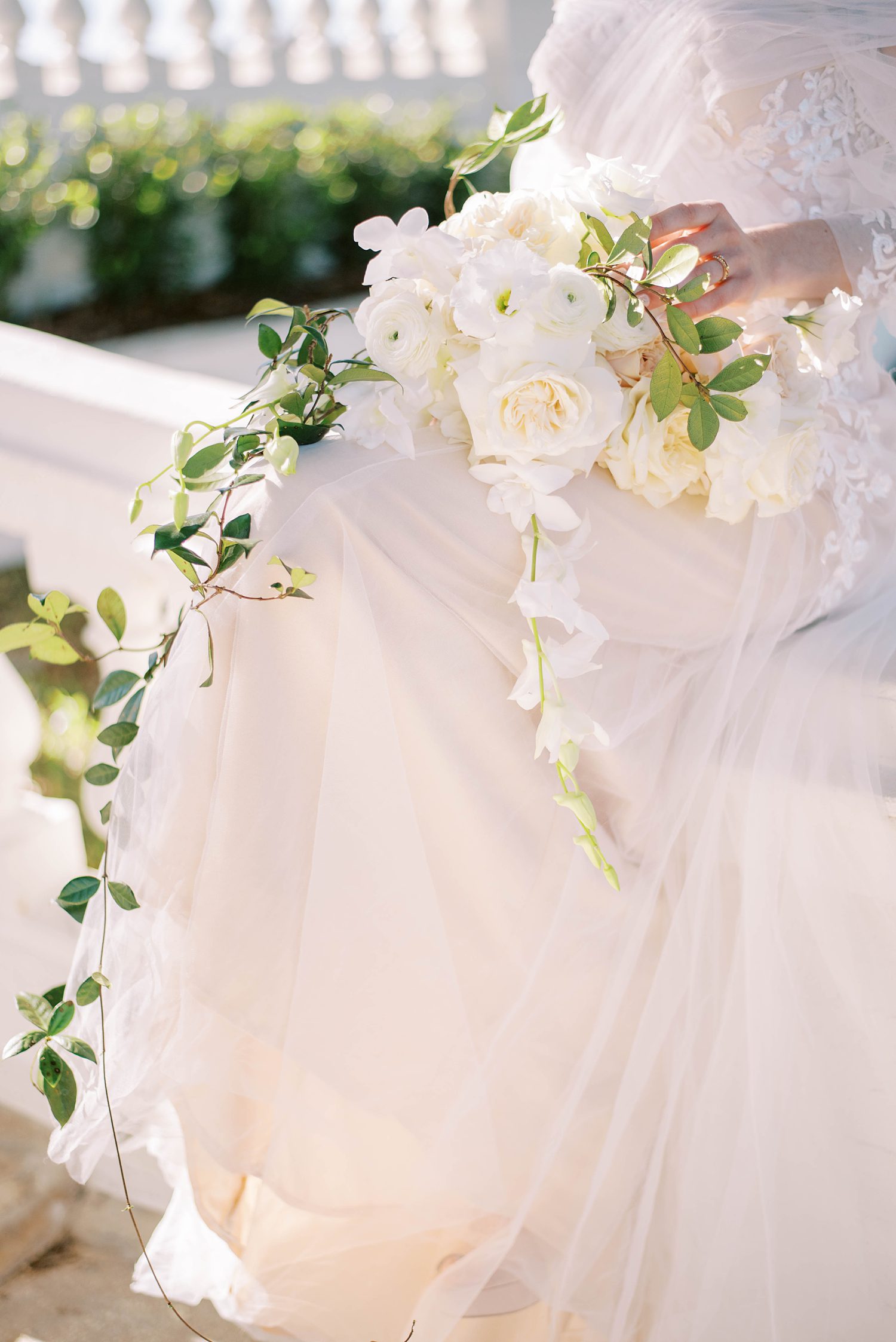 bride holds bouquet of white flowers while sitting on staircase at BellaCosa Lakeside
