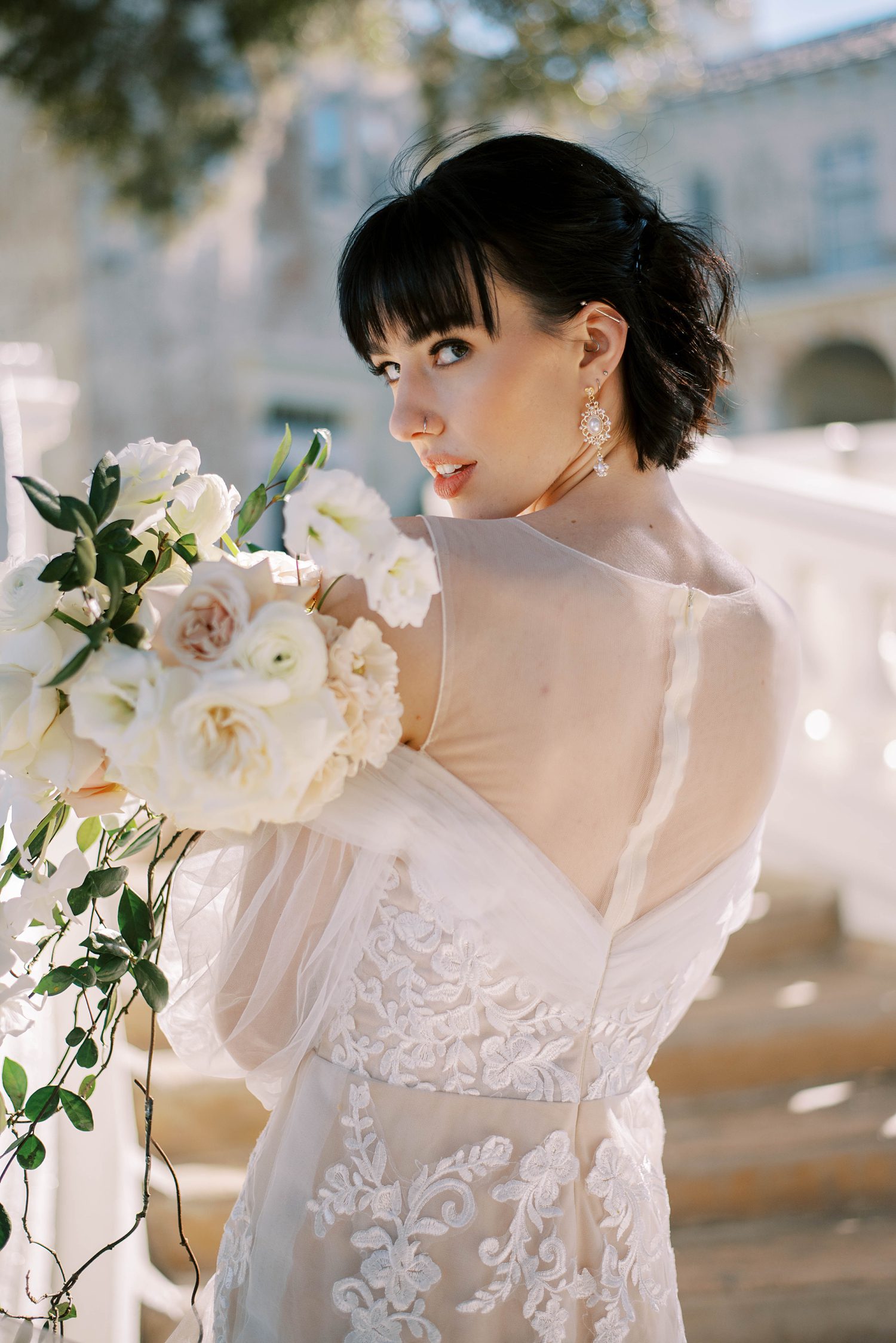 bride holds bouquet of white flowers over shoulder