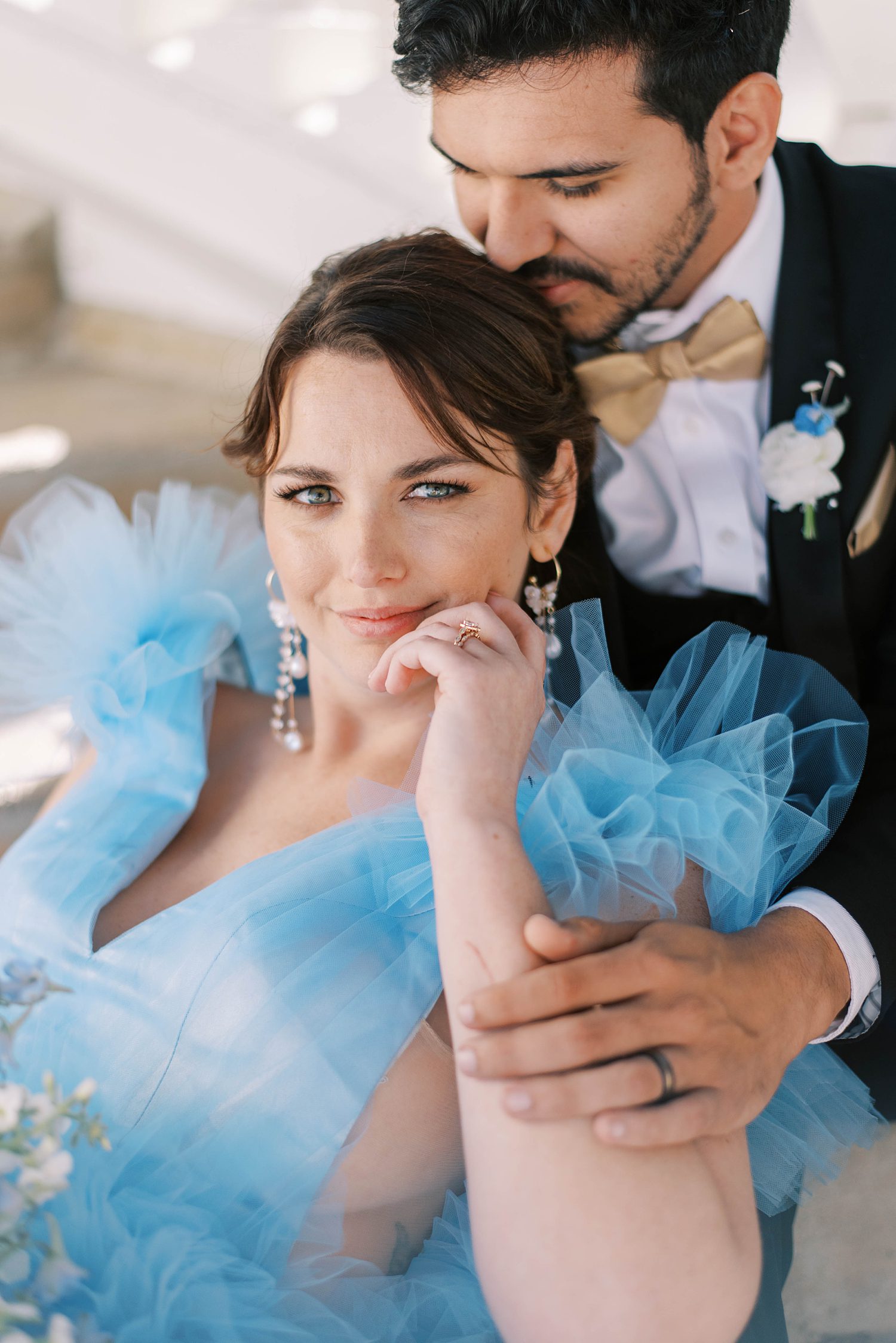 woman in blue gown leans on groom's leg