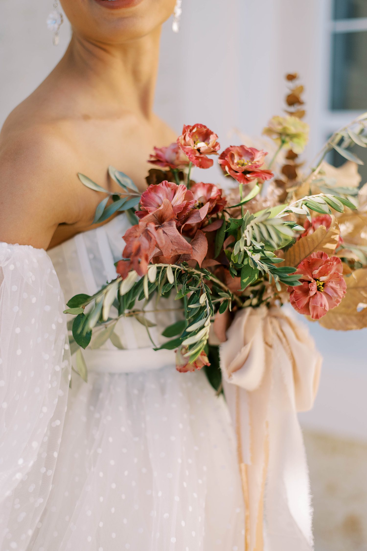 bride holds bouquet of muted pink flowers