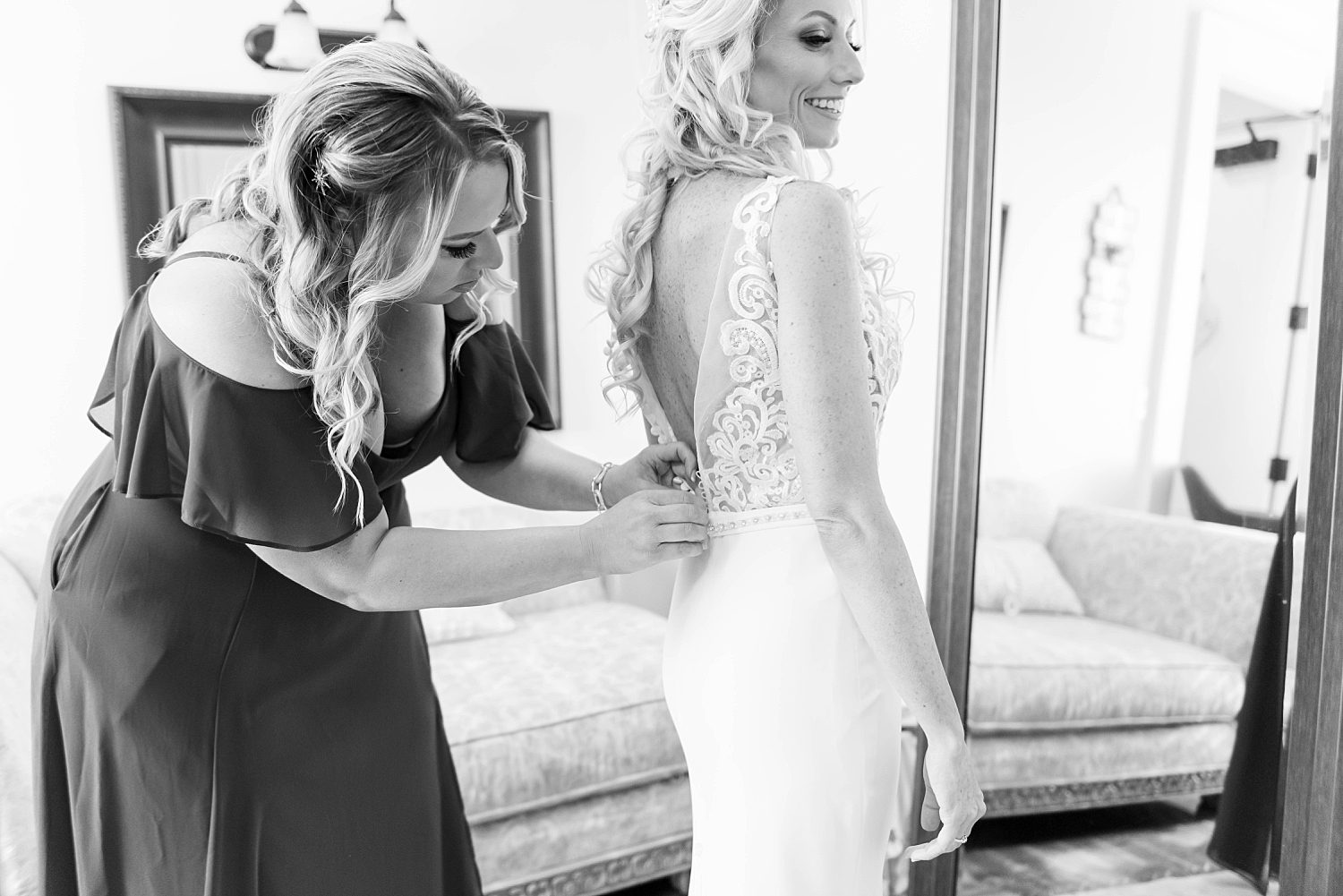 mother helps bride with wedding gown