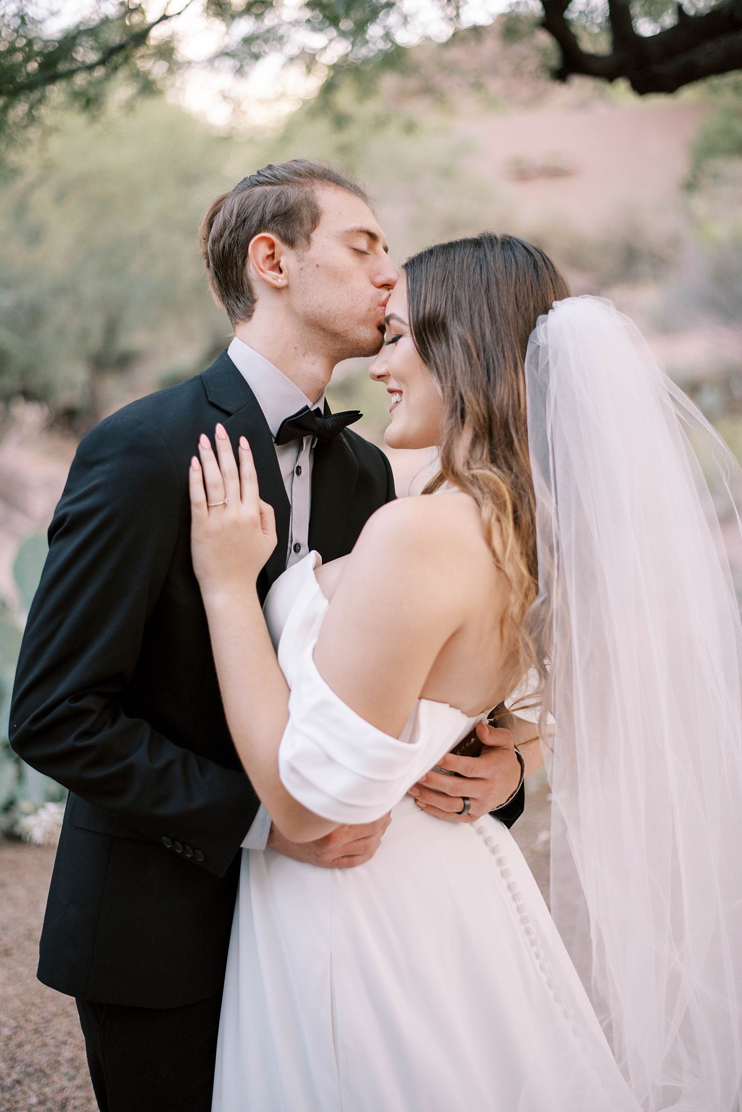 groom kisses bride's forehead during Arizona wedding photos