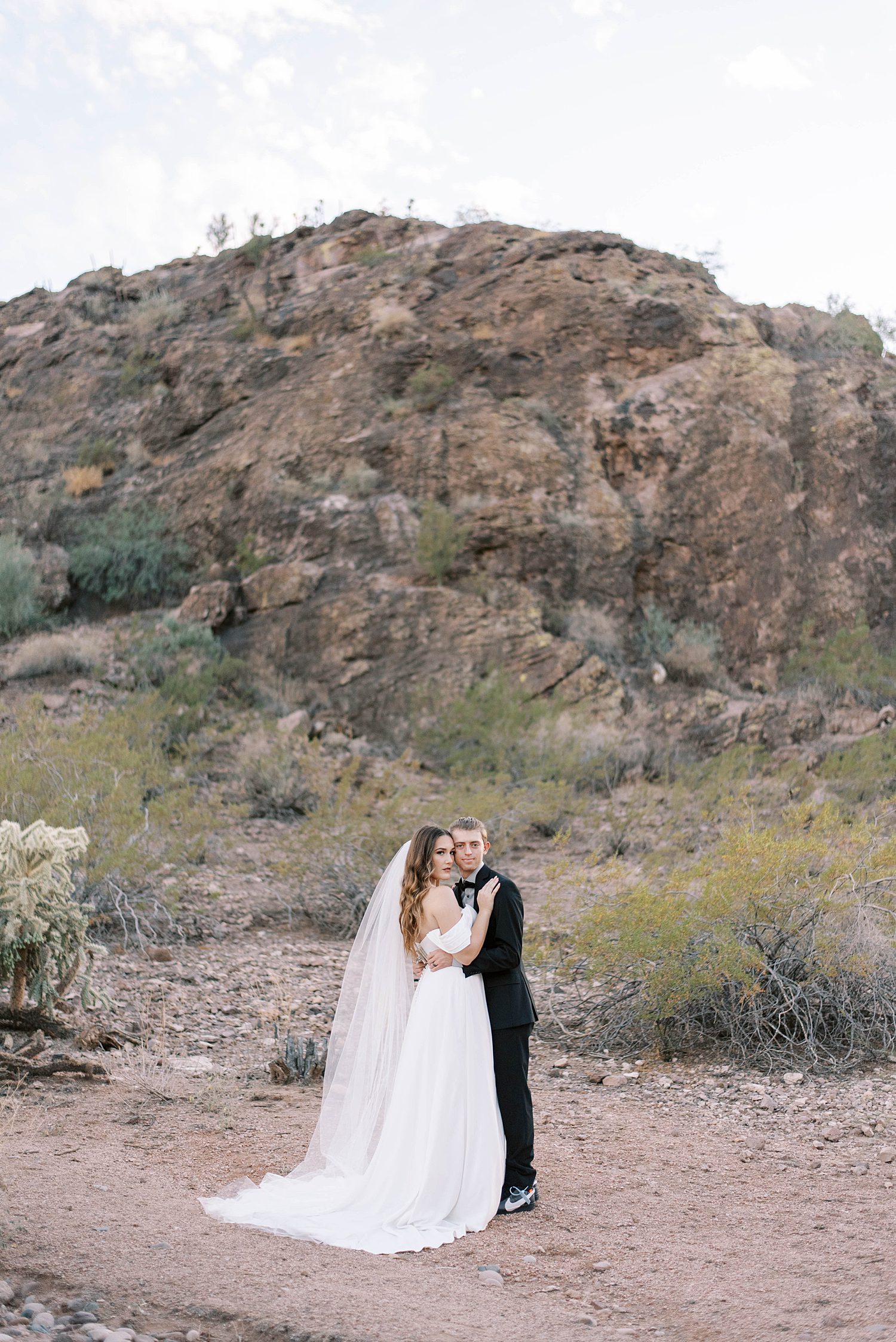 newlyweds kiss by rock formation at Buttes Marriott Hotel