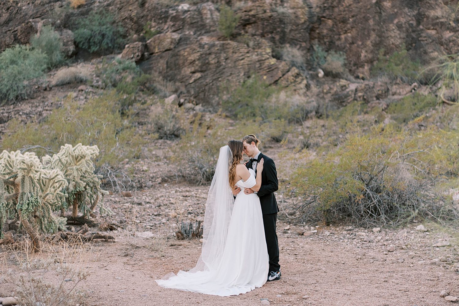 bride and groom kiss by rocks in Arizona desert