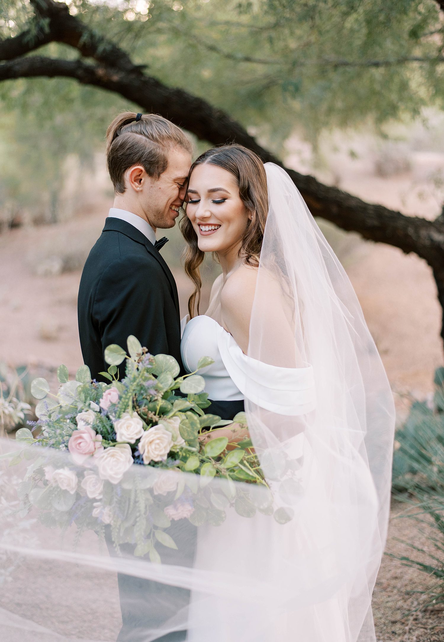 bride and groom laugh under tree during Arizona wedding day