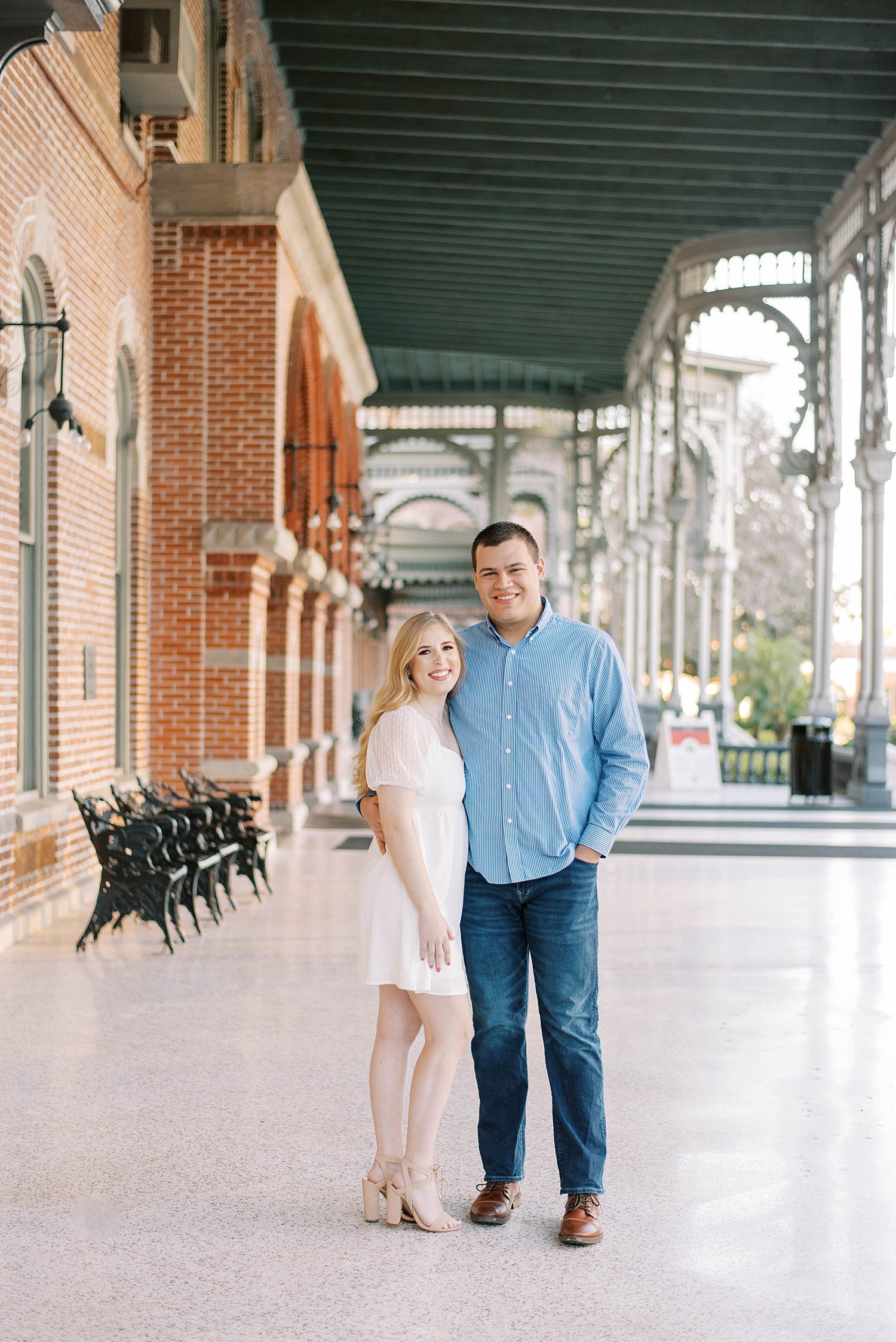 engaged couple stands under green and white awning at the University of Tampa
