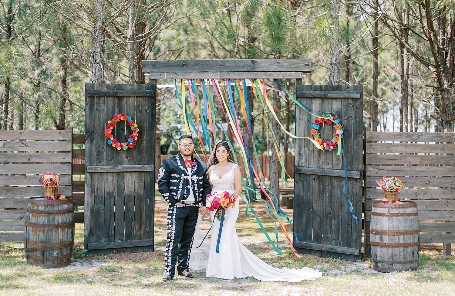 bride and groom stand by rustic wedding ceremony site with colorful streamers
