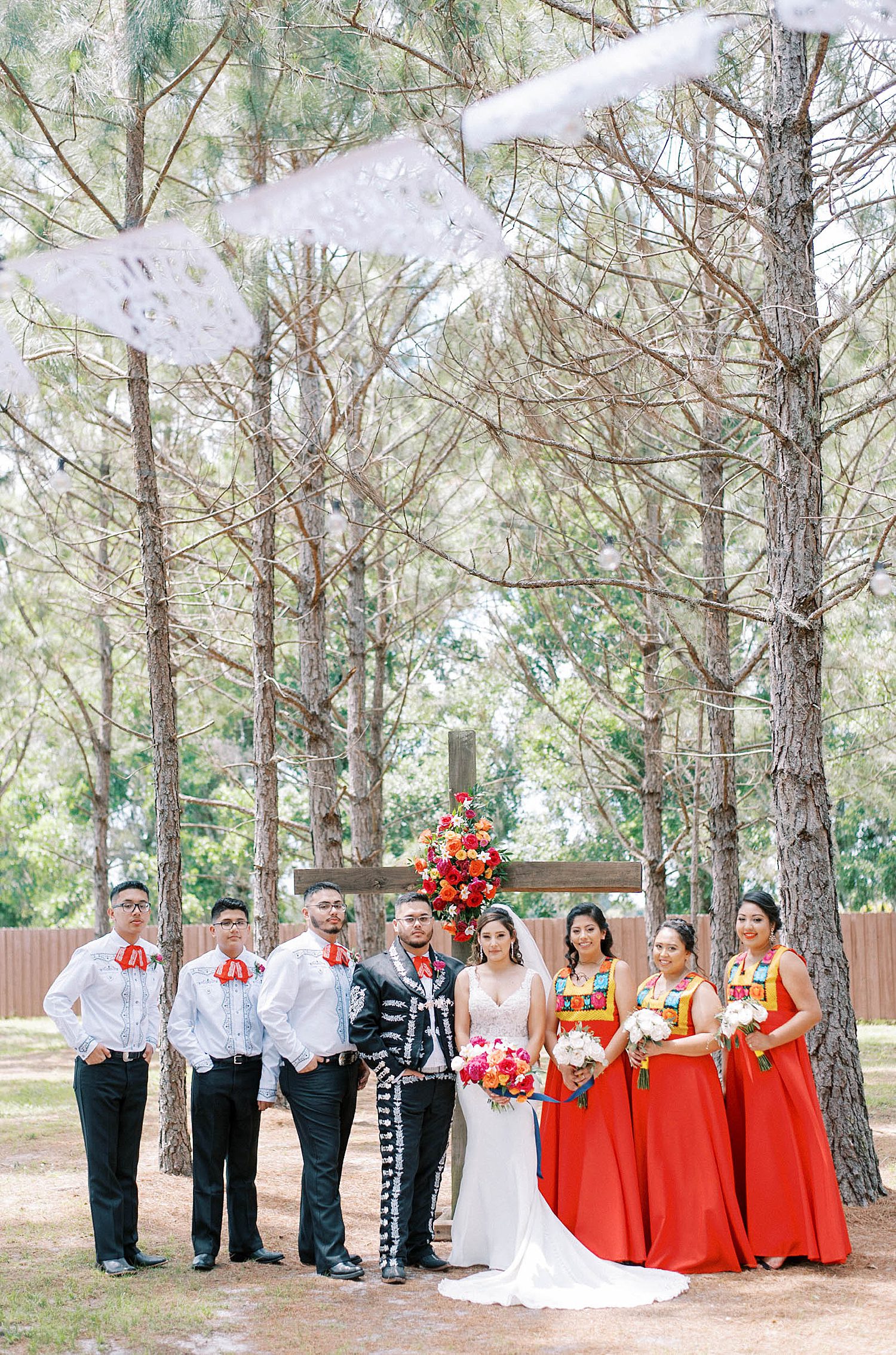 newlyweds stand with wedding party in colorful Mexican dresses