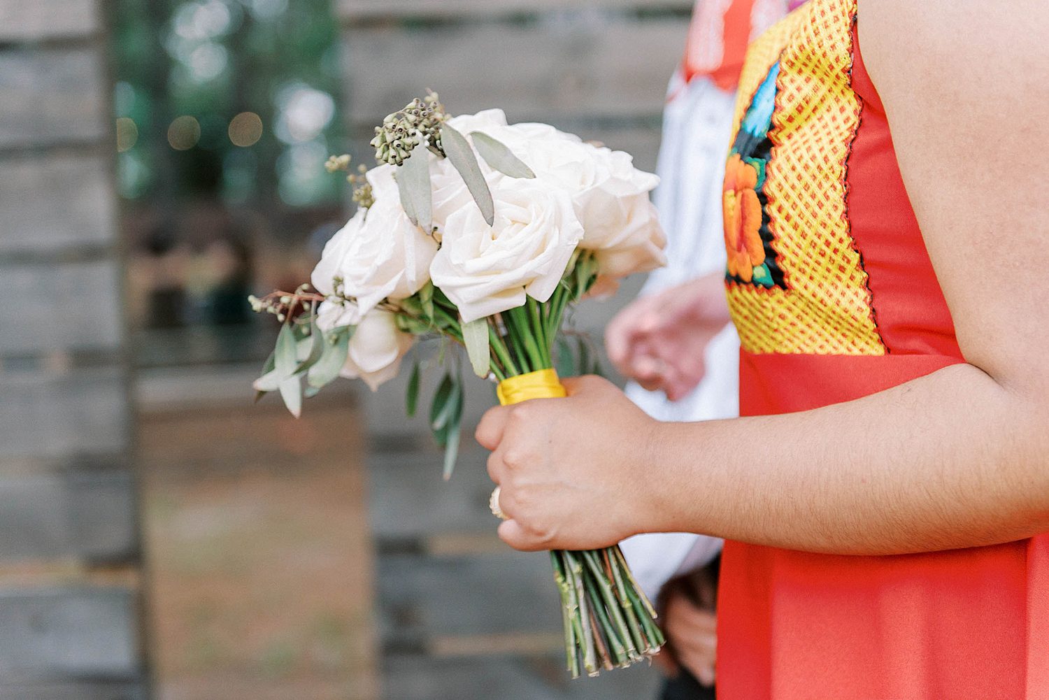 bridesmaid holds small bouquet of white roses for Mexican inspired wedding