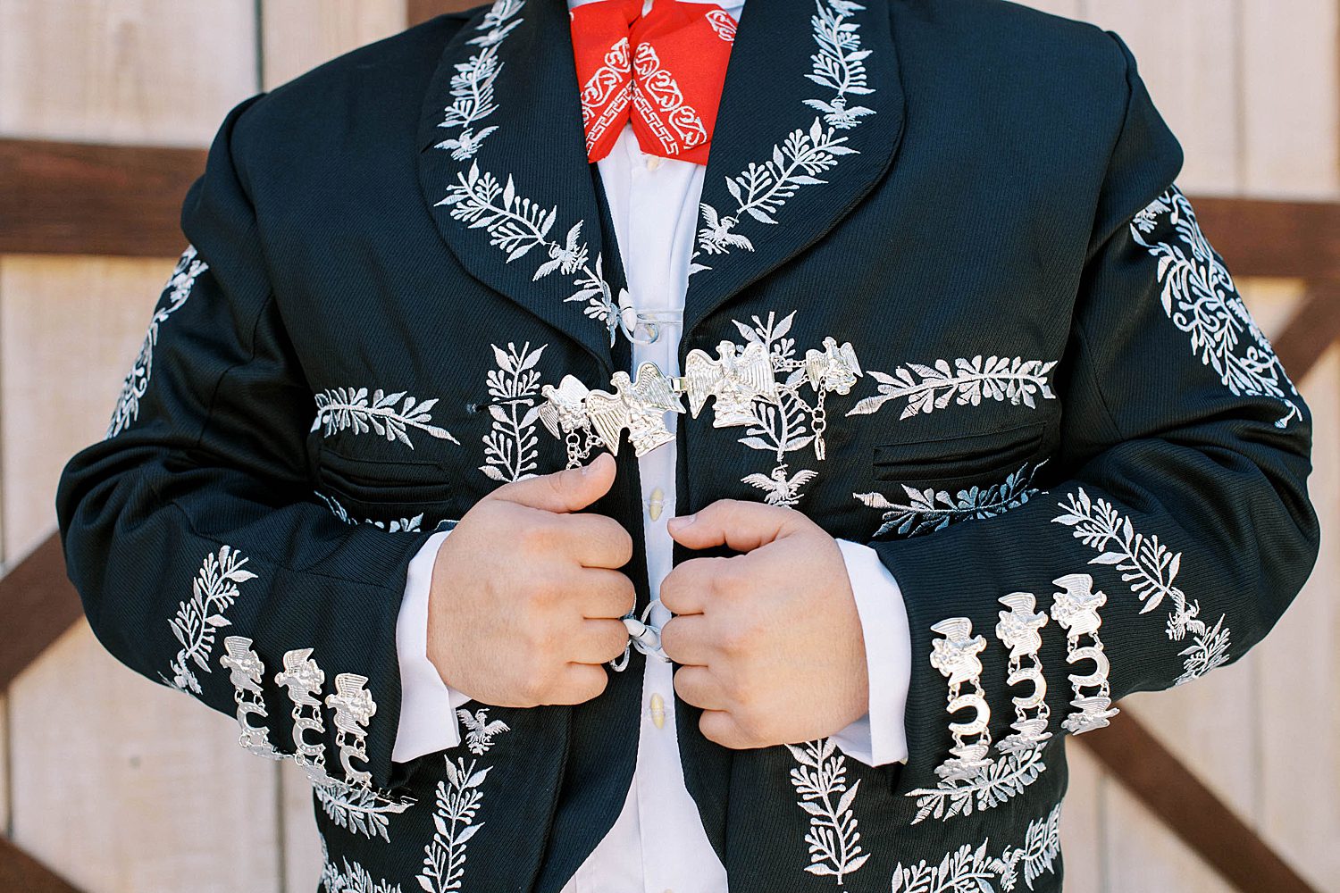 groom pulls custom black jacket made in Mexico closed