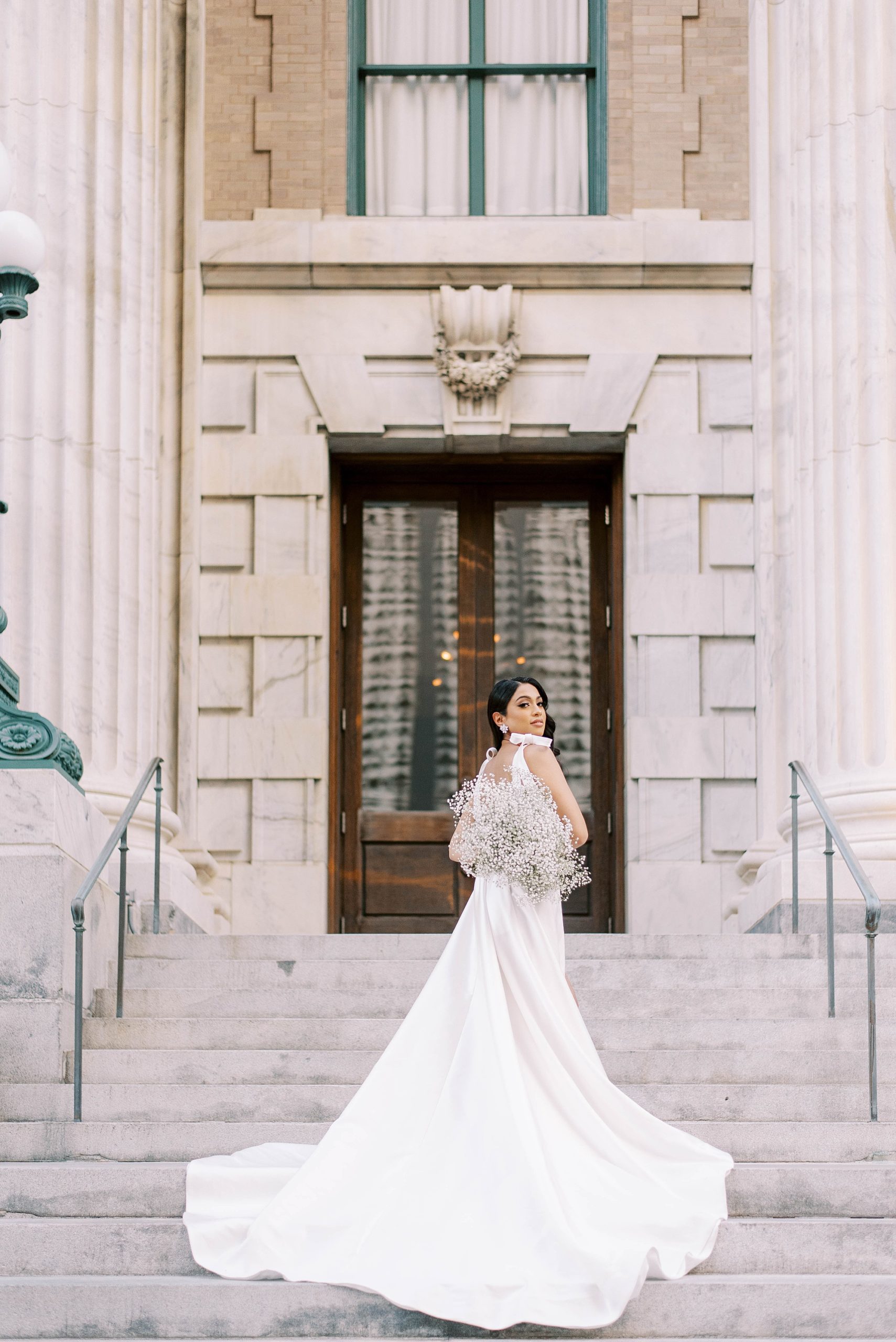 woman stands on steps with train spread of Delana Muse gown