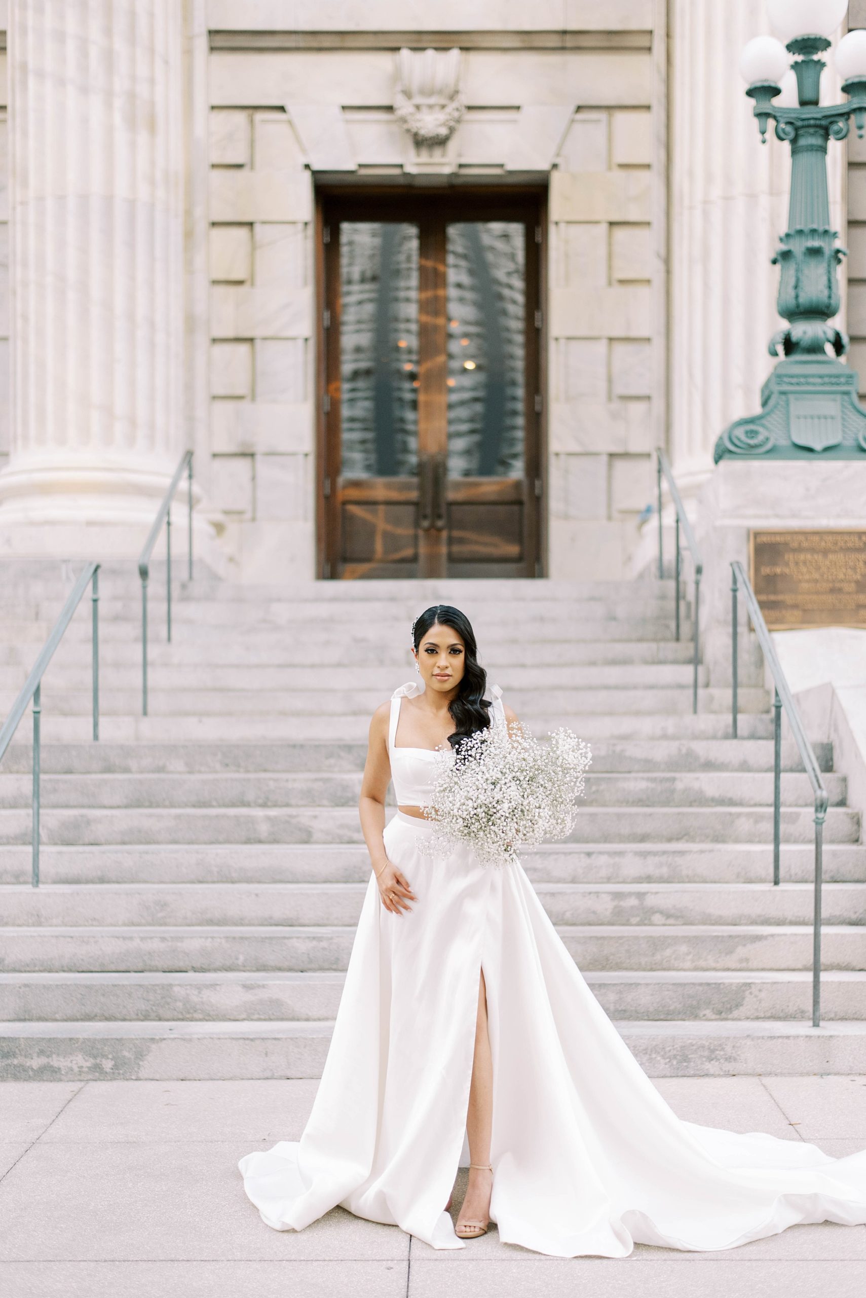woman walks down courthouse steps in modern white wedding gown