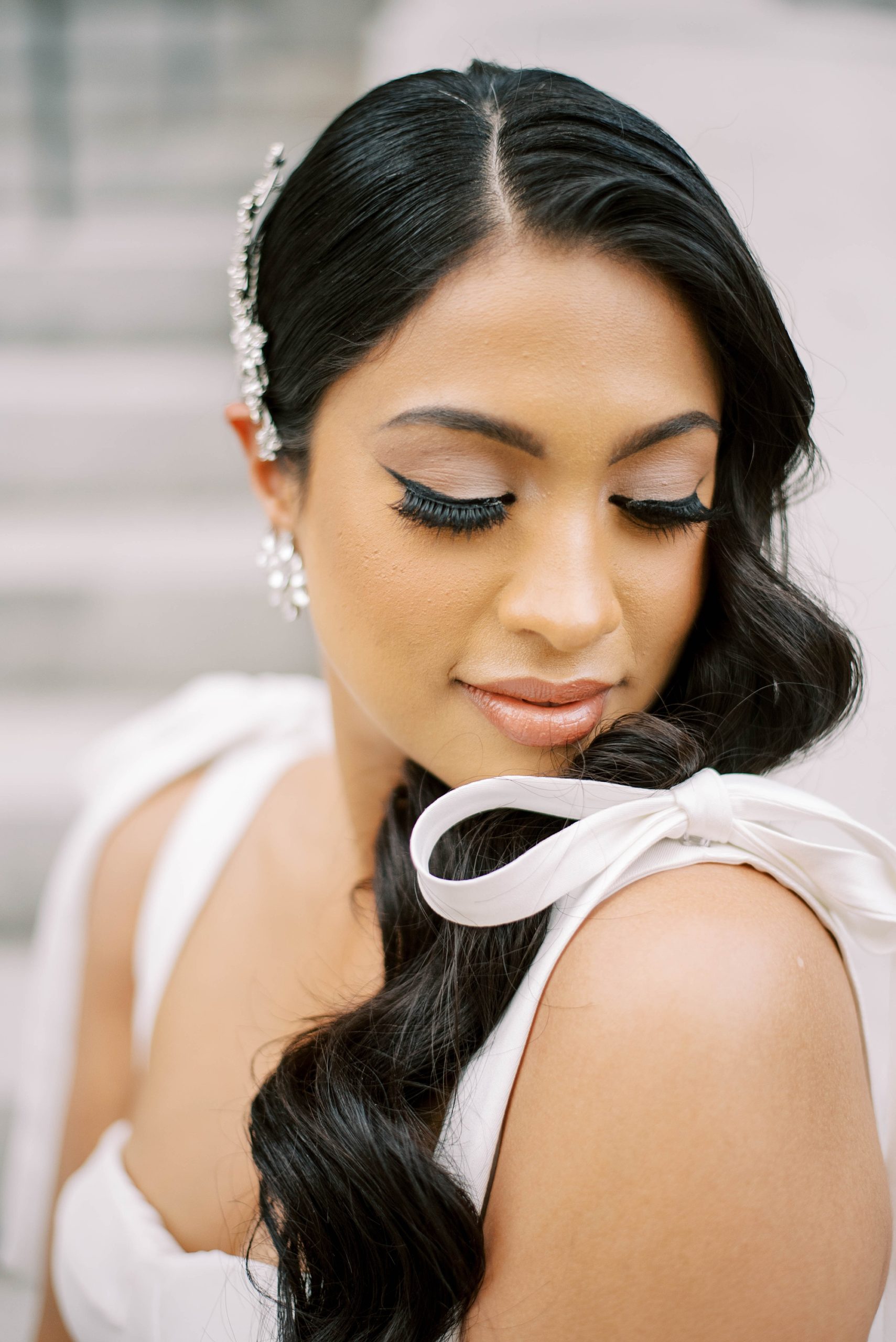 bride looks at bow on shoulder of Delana Muse gown