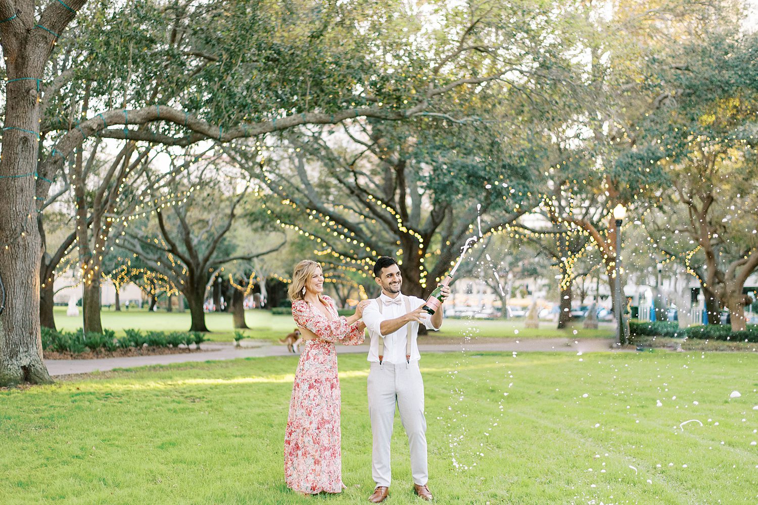 bride and groom pop champagne in park