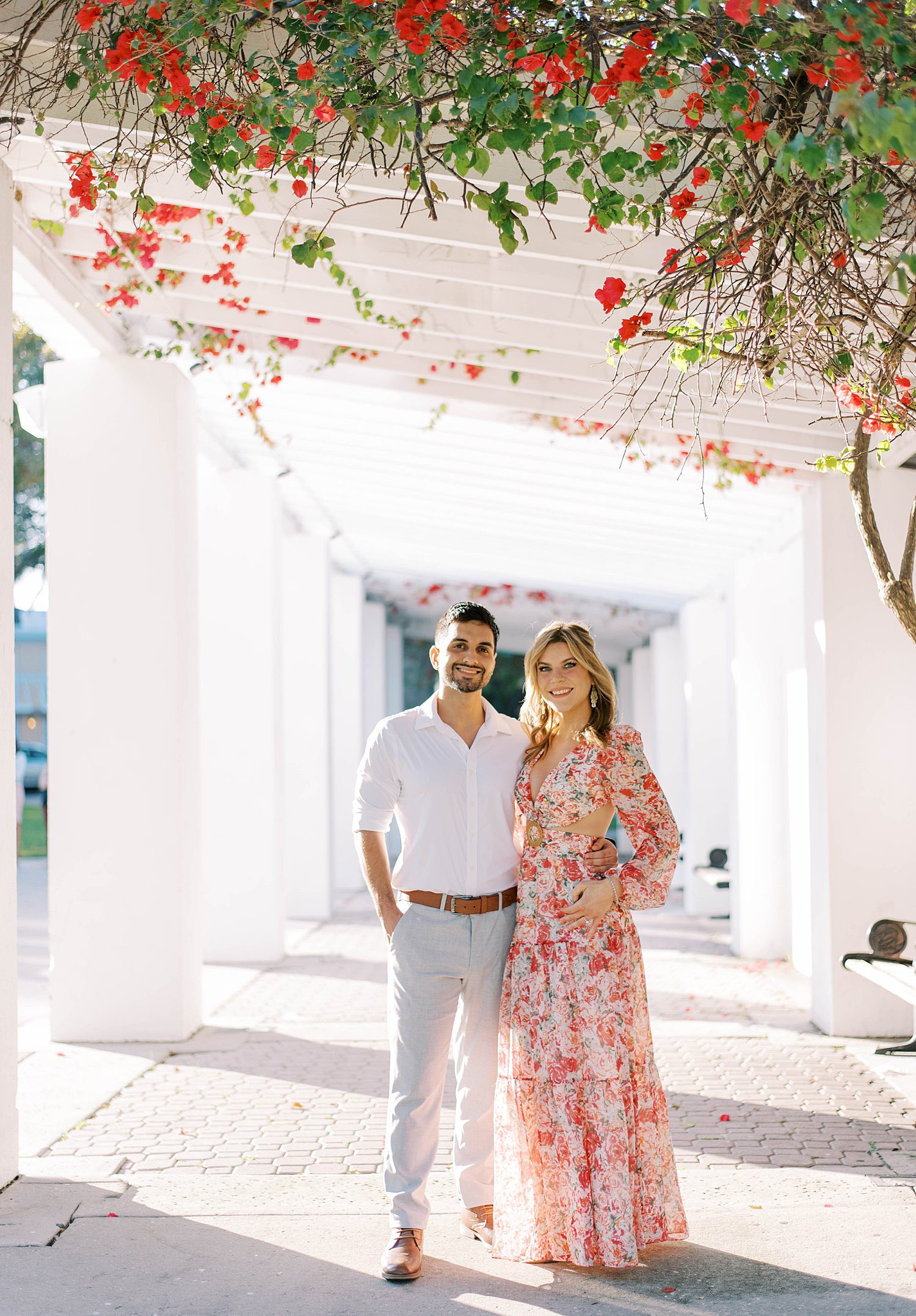 engaged couple stands together under red flowers at the Vinoy Renaissance