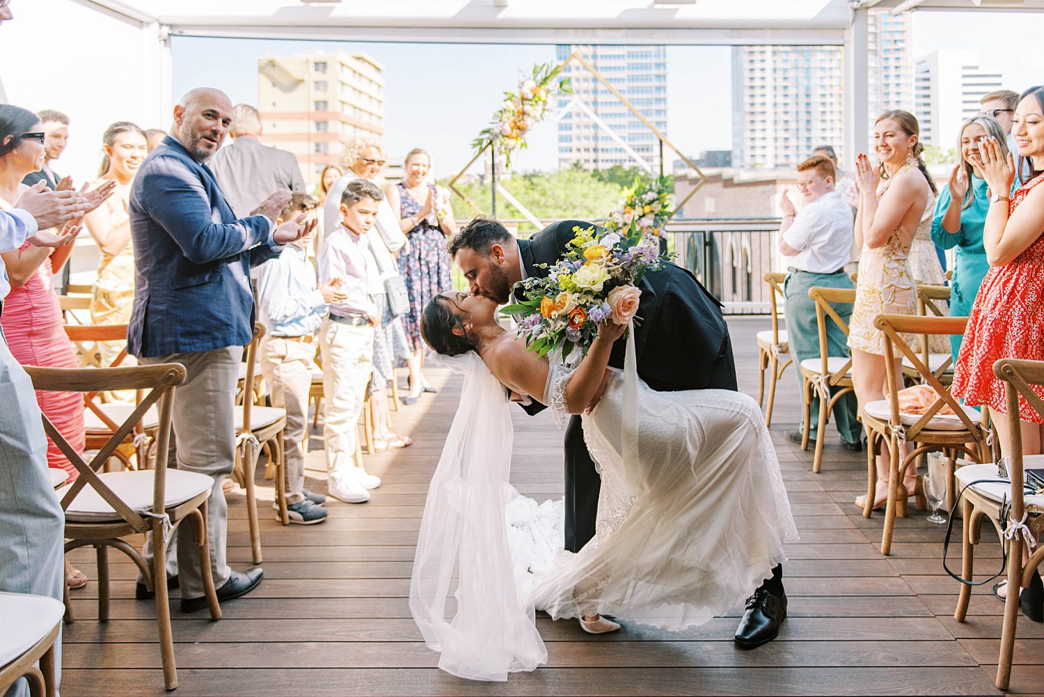 groom dips bride after bilingual wedding ceremony on rooftop of Red Mesa Cantina