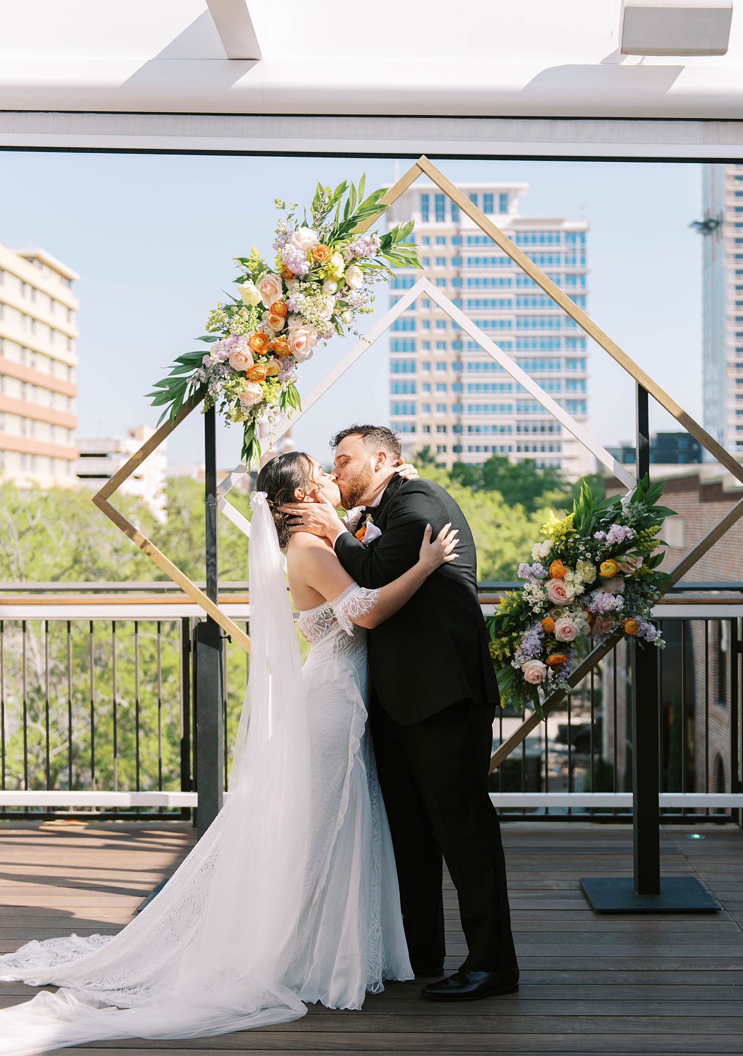 newlyweds kiss under gold arbor on rooftop of St. Pete FL restaurant