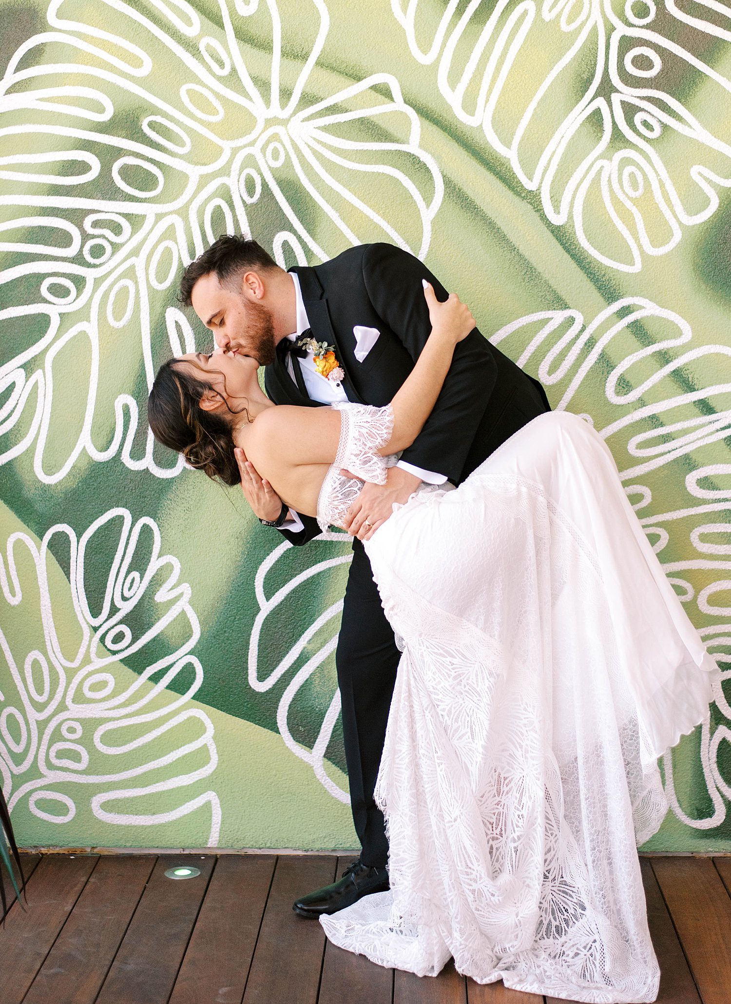 groom dips bride by palm tree artwork at Red Mesa Cantina