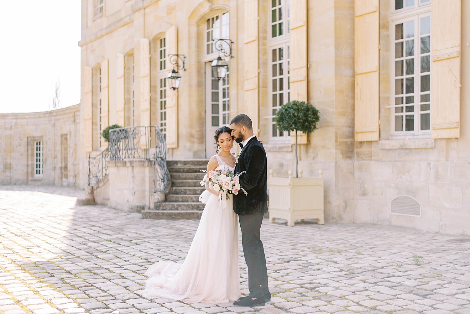 bride and groom stand together outside Chateau de Villette in Paris France