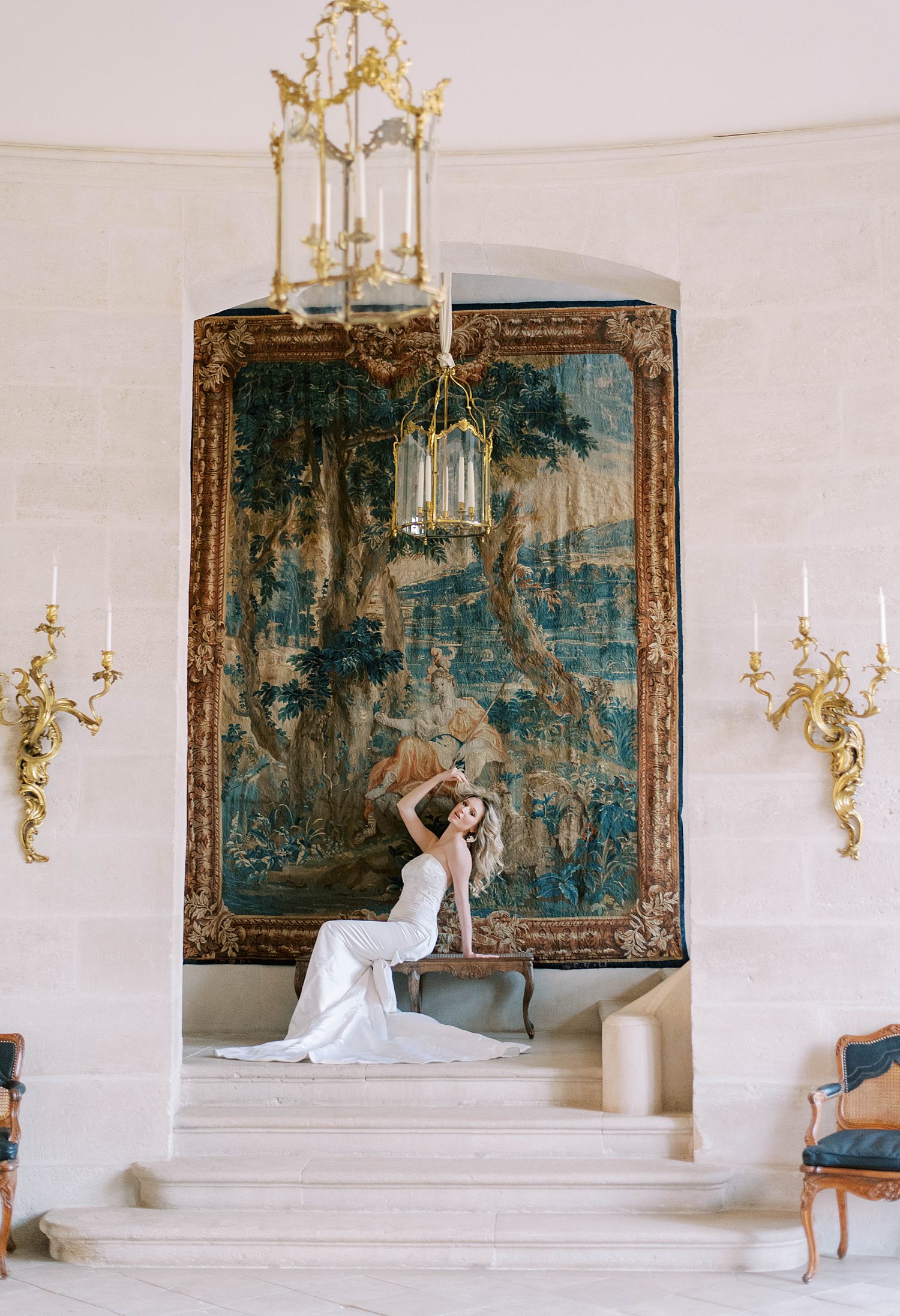 bride in chic Marchesa gown poses in front of dramatic painting at Chateau de Villette