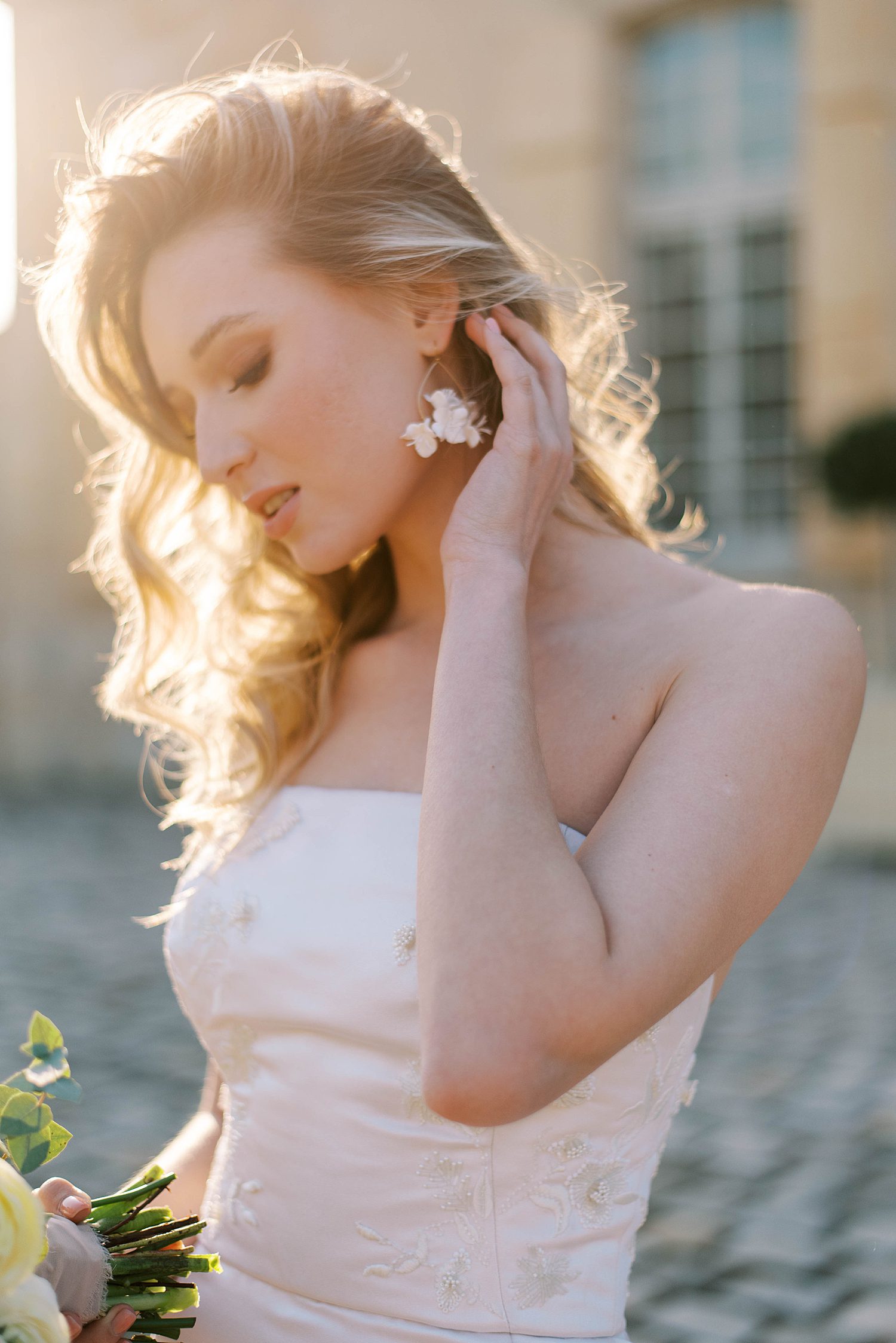 bride pushes hair over shoulder in chic wedding gown at sunset