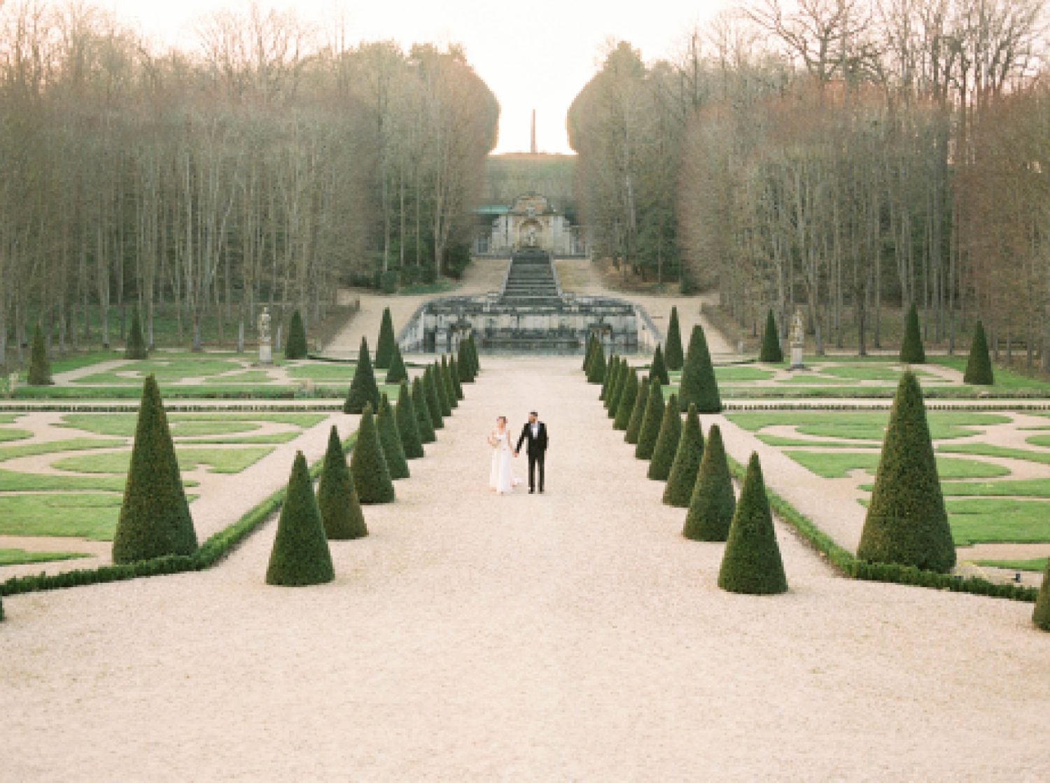 newlyweds walk down pathway outside Chateau de Villette