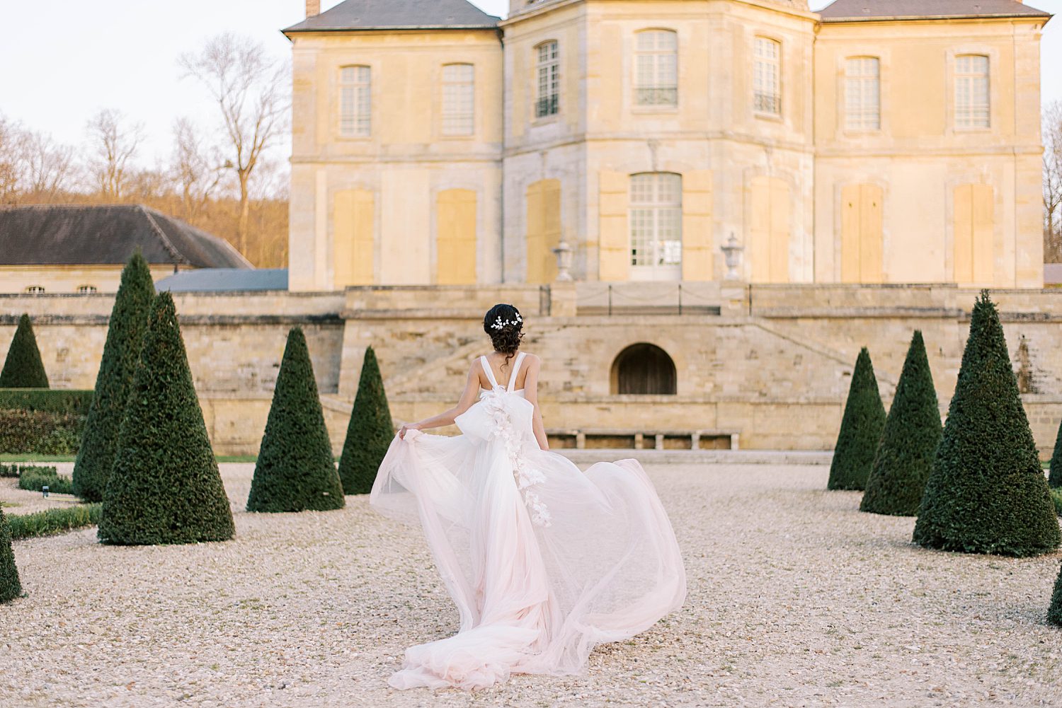 bride runs down pathway outside Chateau de Villette with skirt blowing in wind