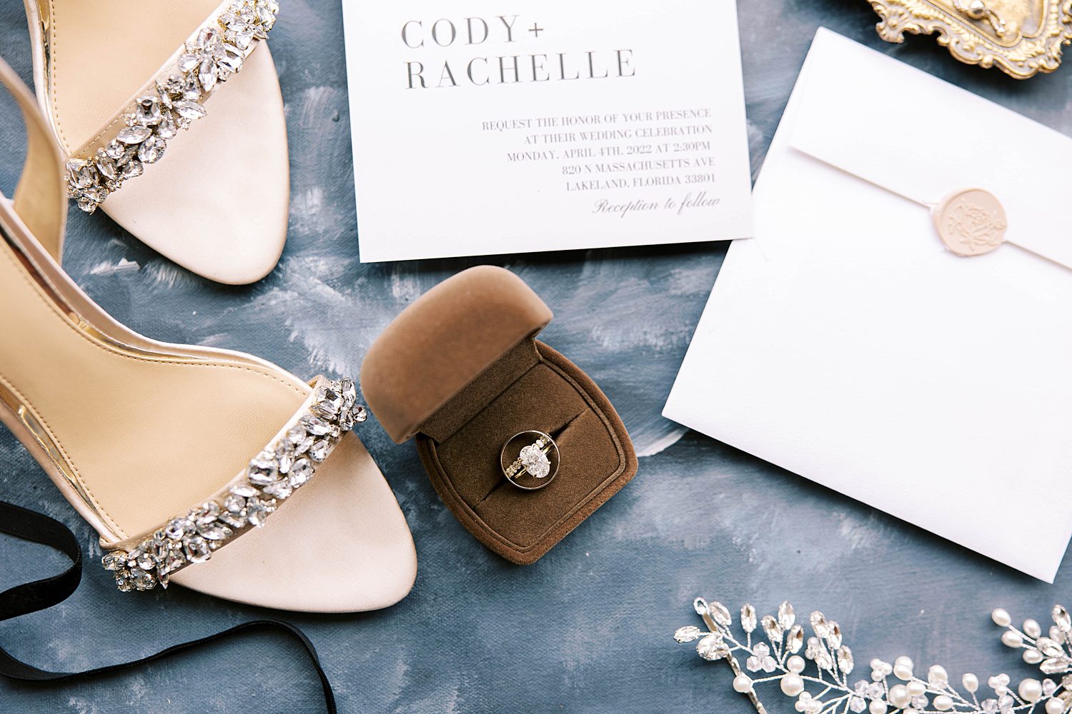 bride's diamond ring rests in brown box by silver shoes