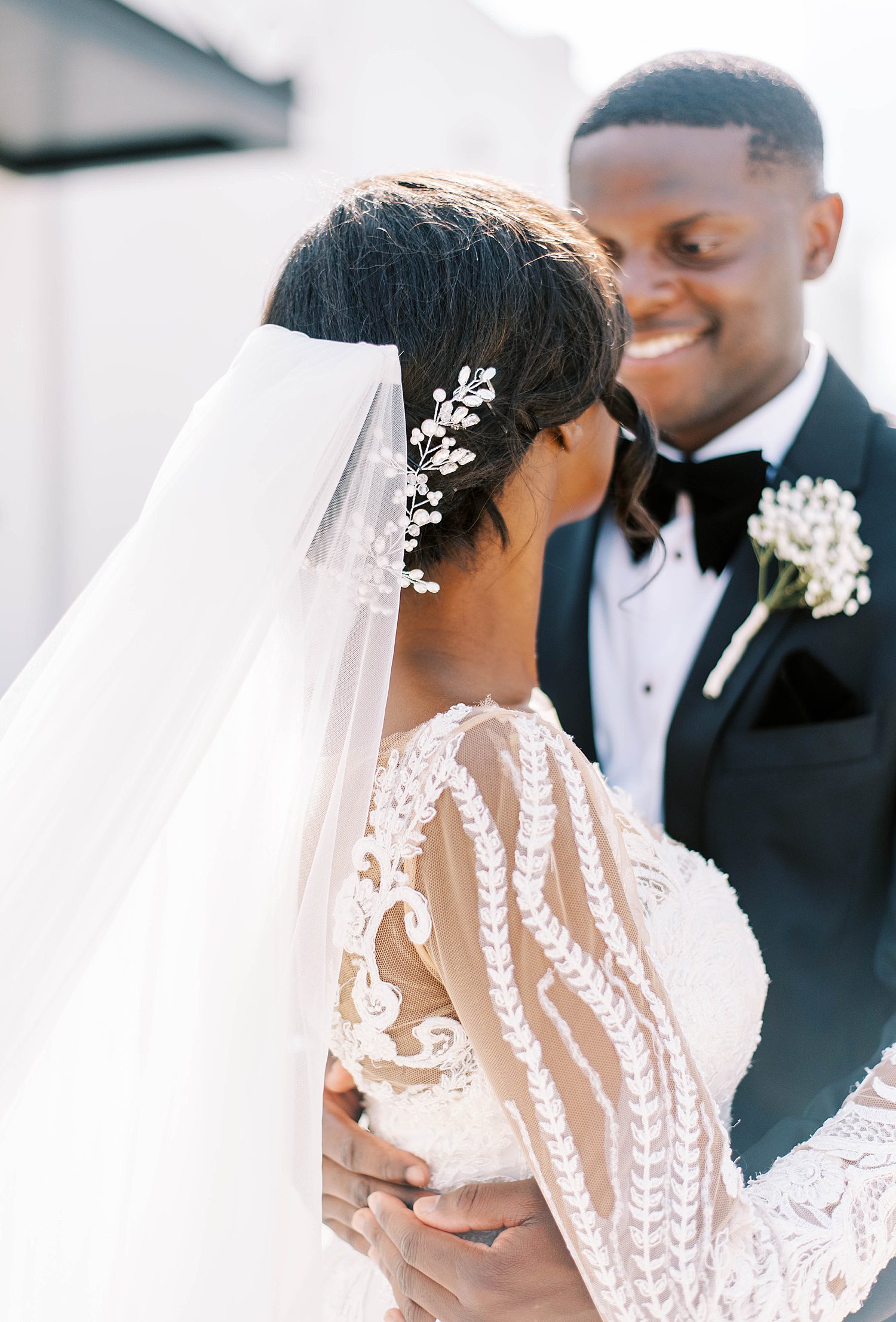 bride and groom smile together showing off bride's lace details on gown