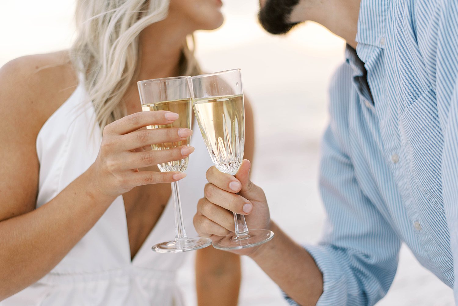 couple toasts champagne glasses on beach during St. Pete engagement session
